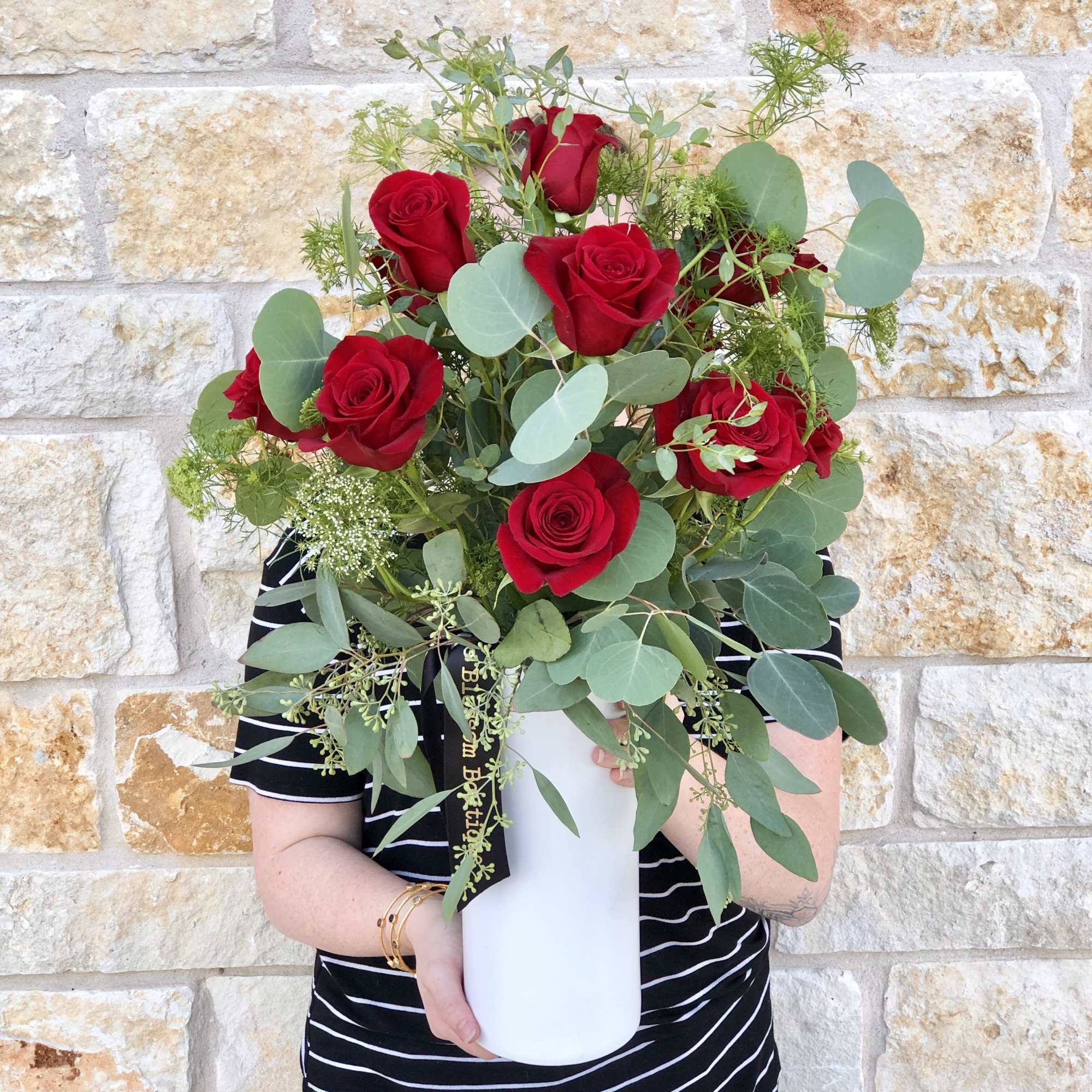 A dozen premium Red roses, accented with seasonal greenery and arranged in