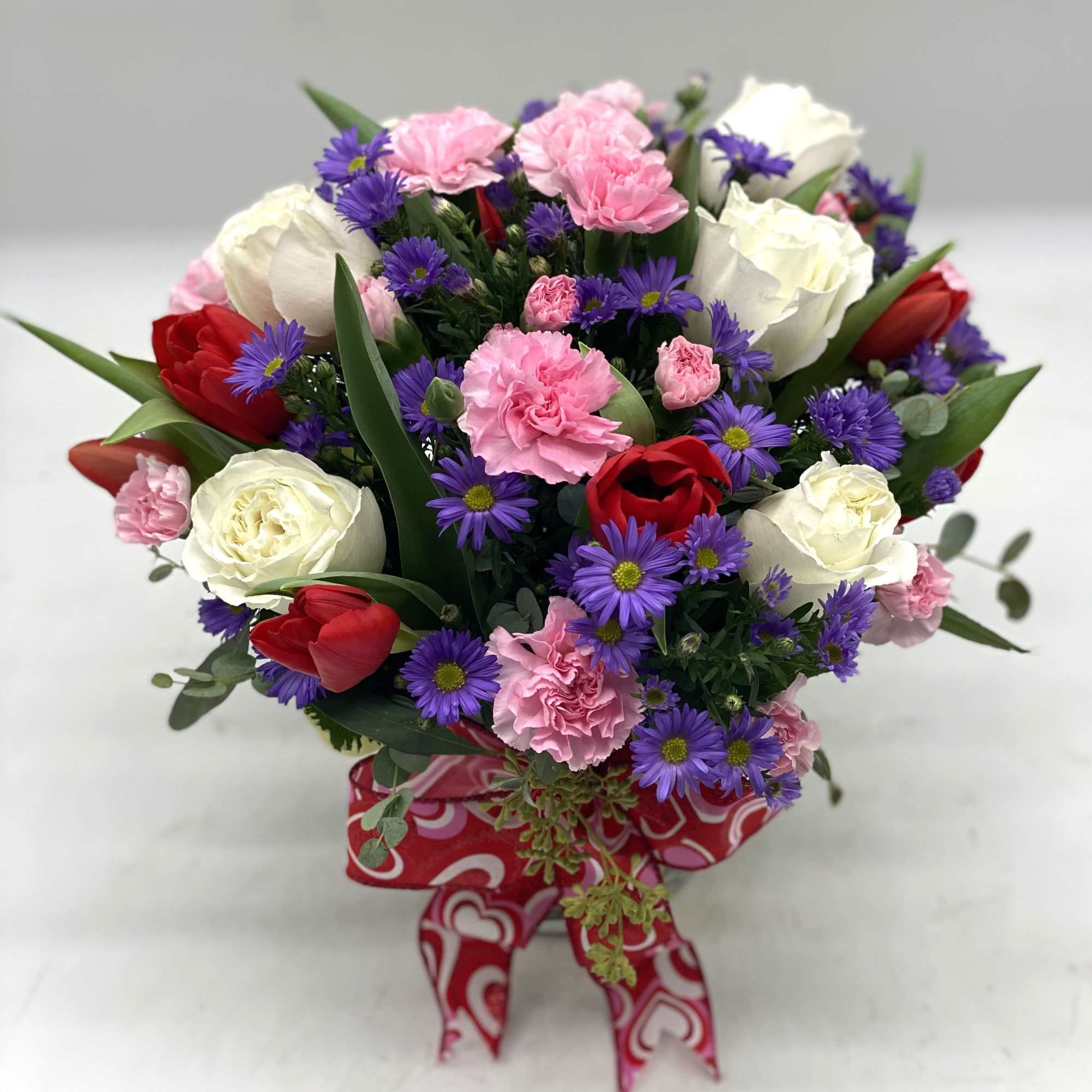 White Roses, Pink Mini Carnations and Red Tulips with Purple Aster accents