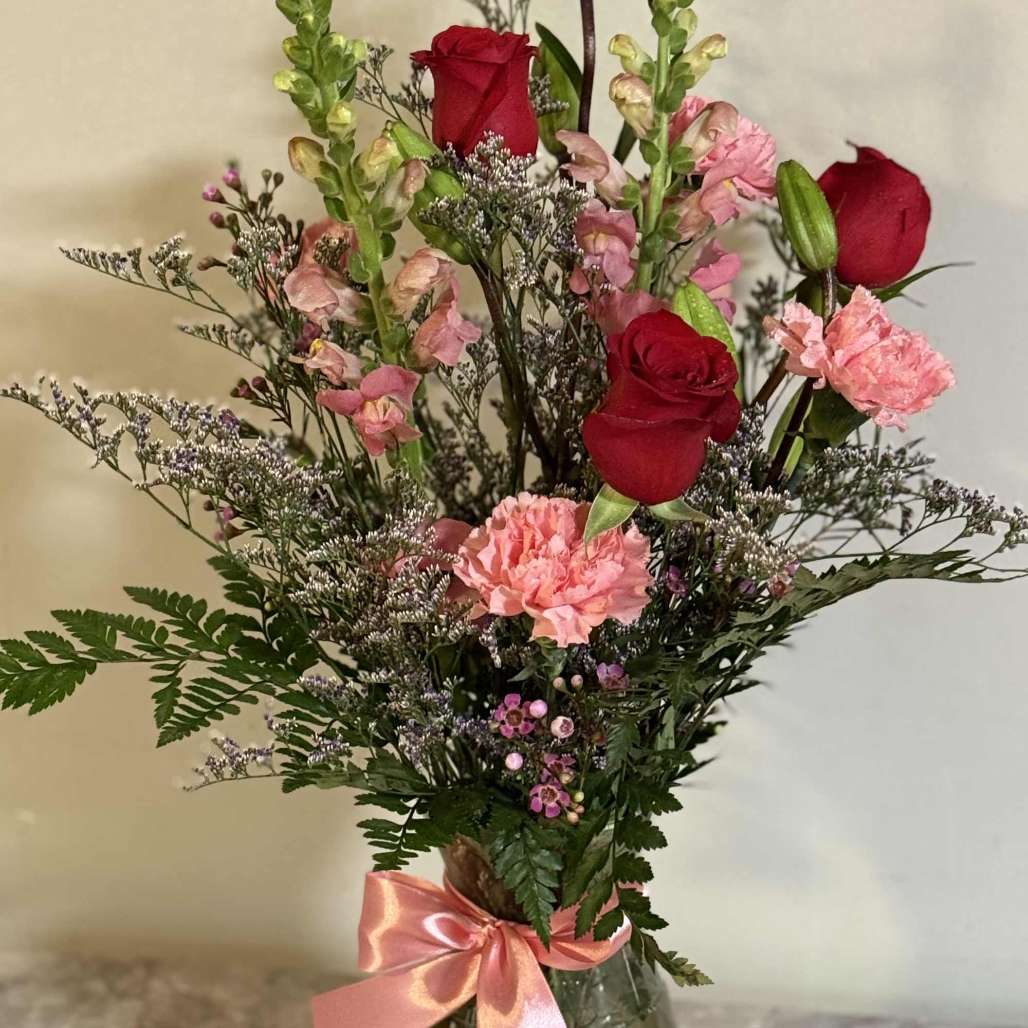 Red rose and pink snap dragons ,carnations and greens and filler 