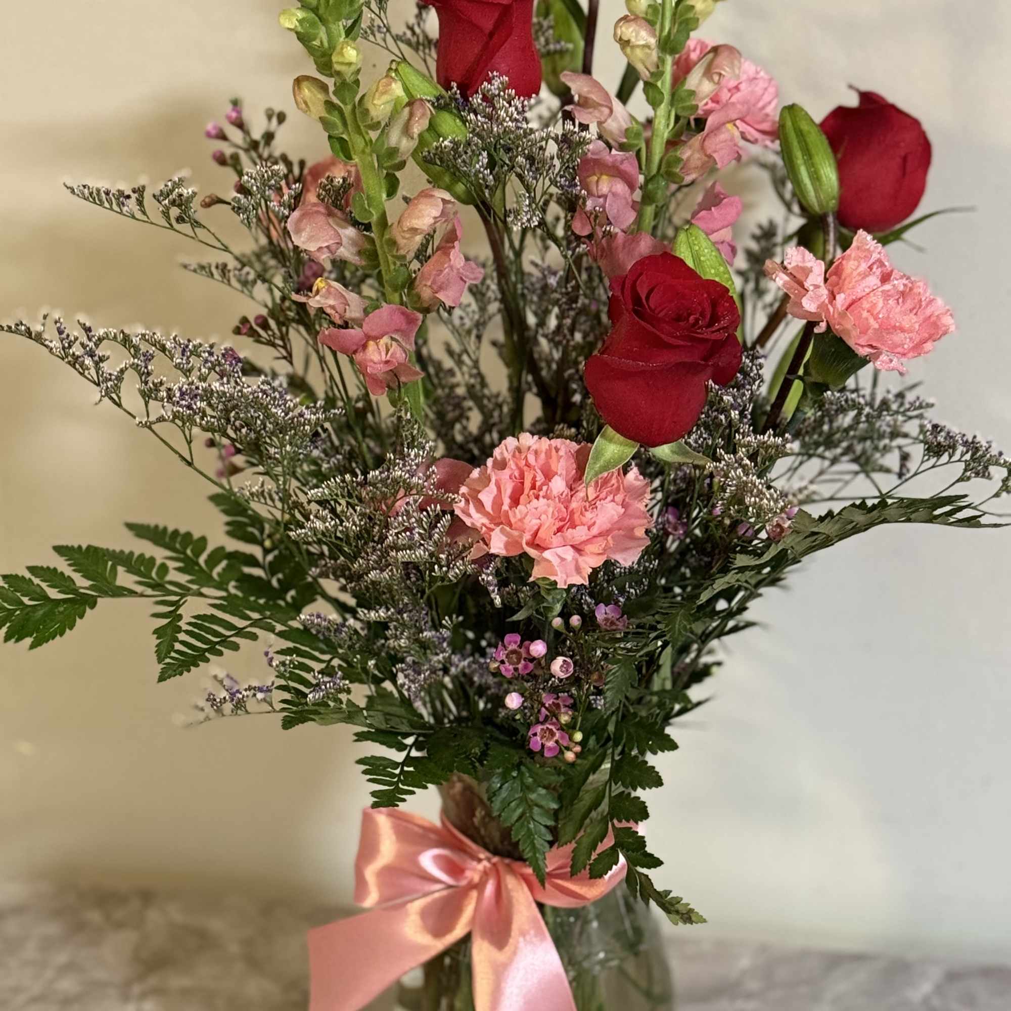 Red rose and pink snap dragons ,carnations and greens and filler 