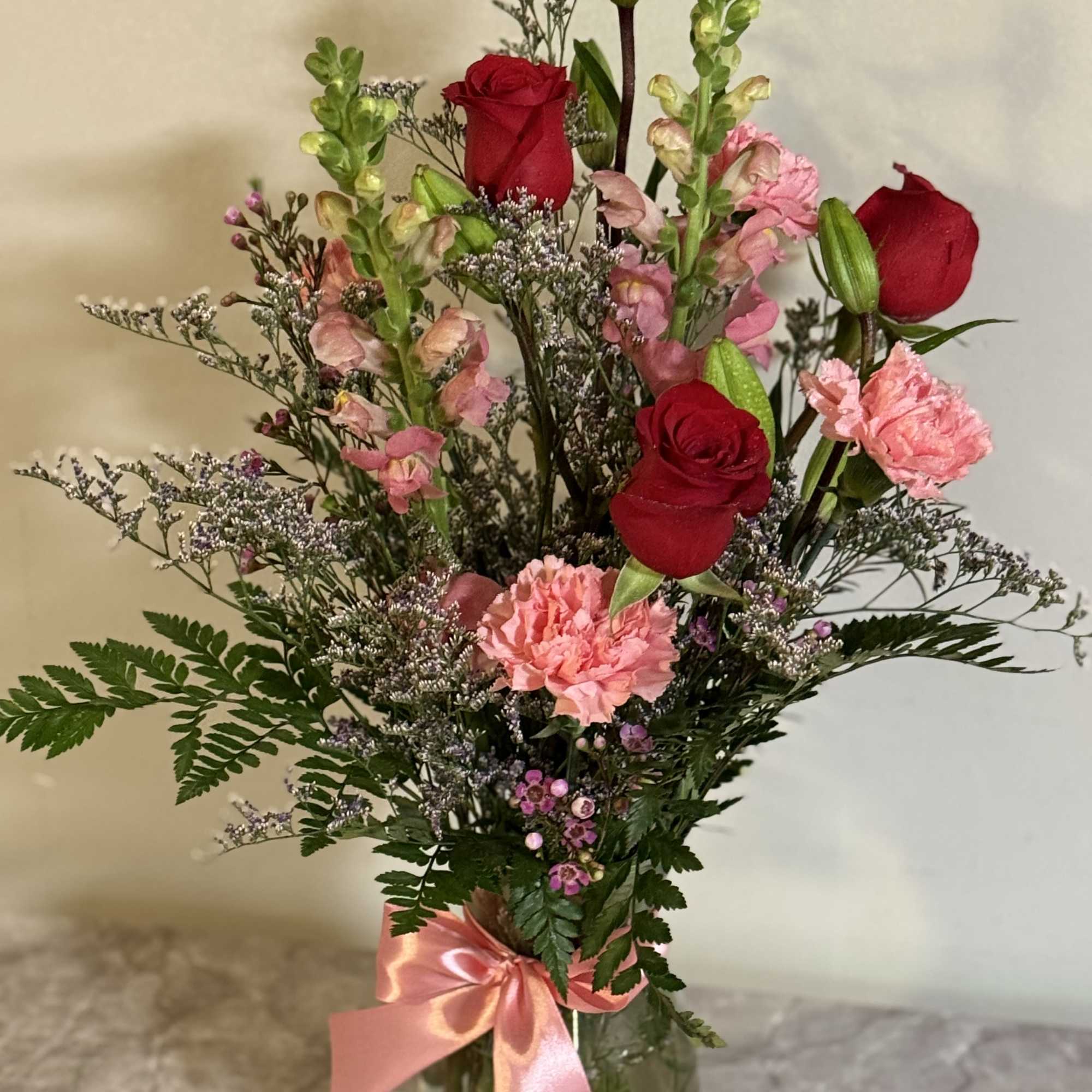 Red rose and pink snap dragons ,carnations and greens and filler 