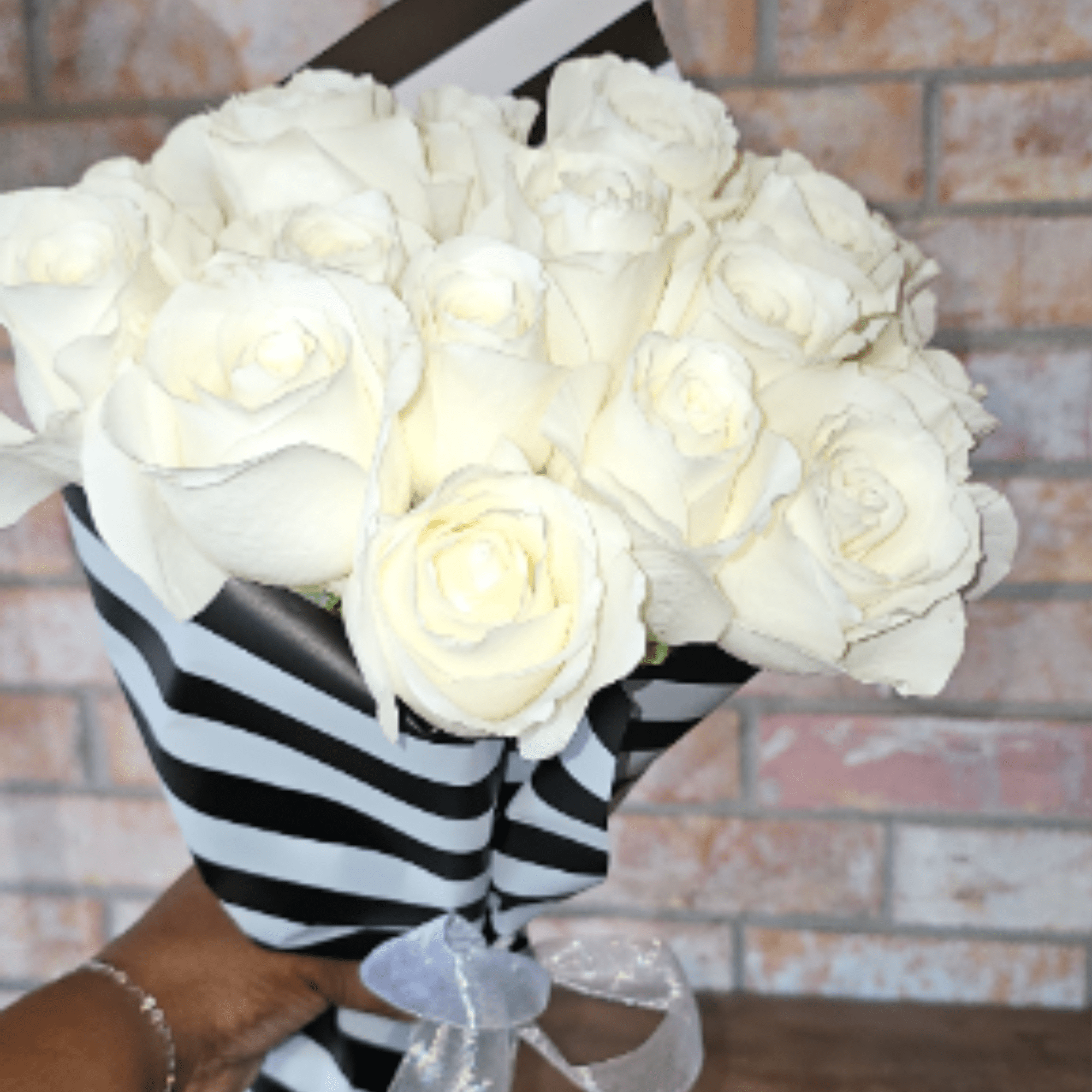 A timeless bouquet of premium ivory roses wrapped in our signature black-and-white