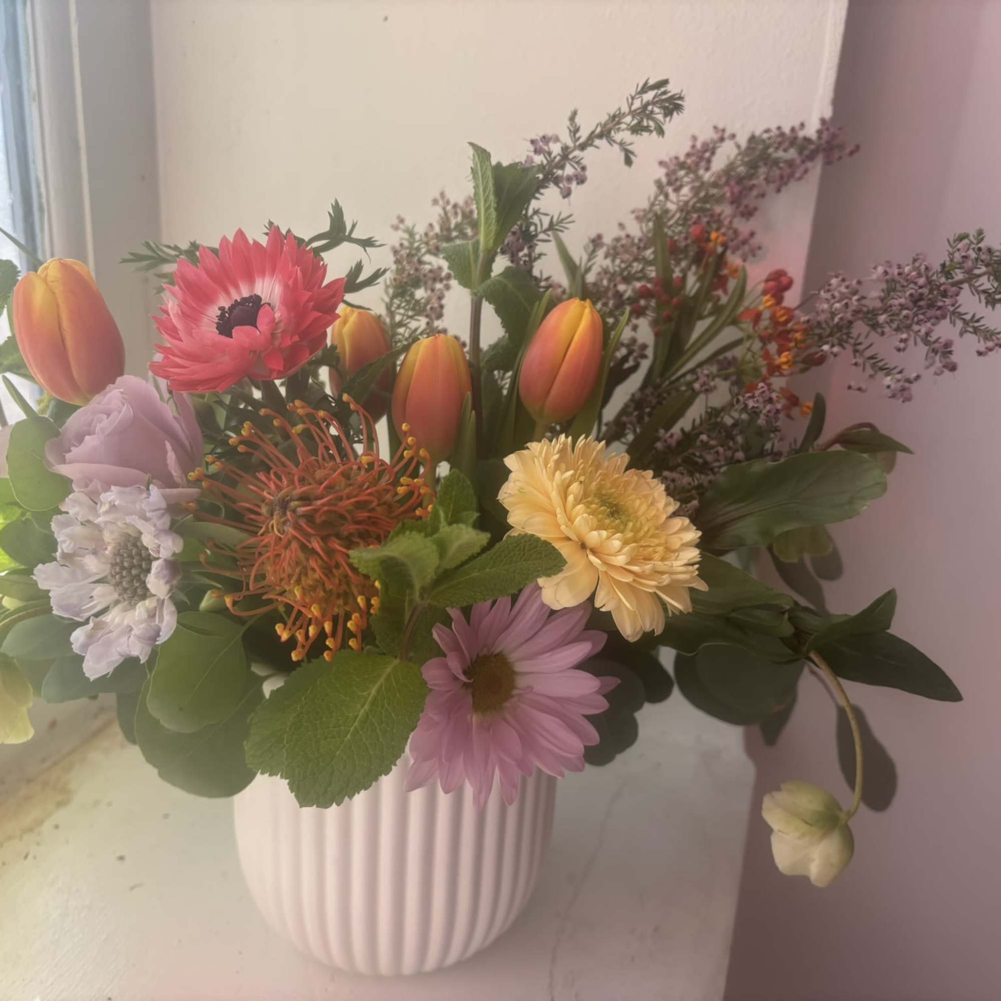 An arrangement that is filled with delight, colorful local tulips and anemones