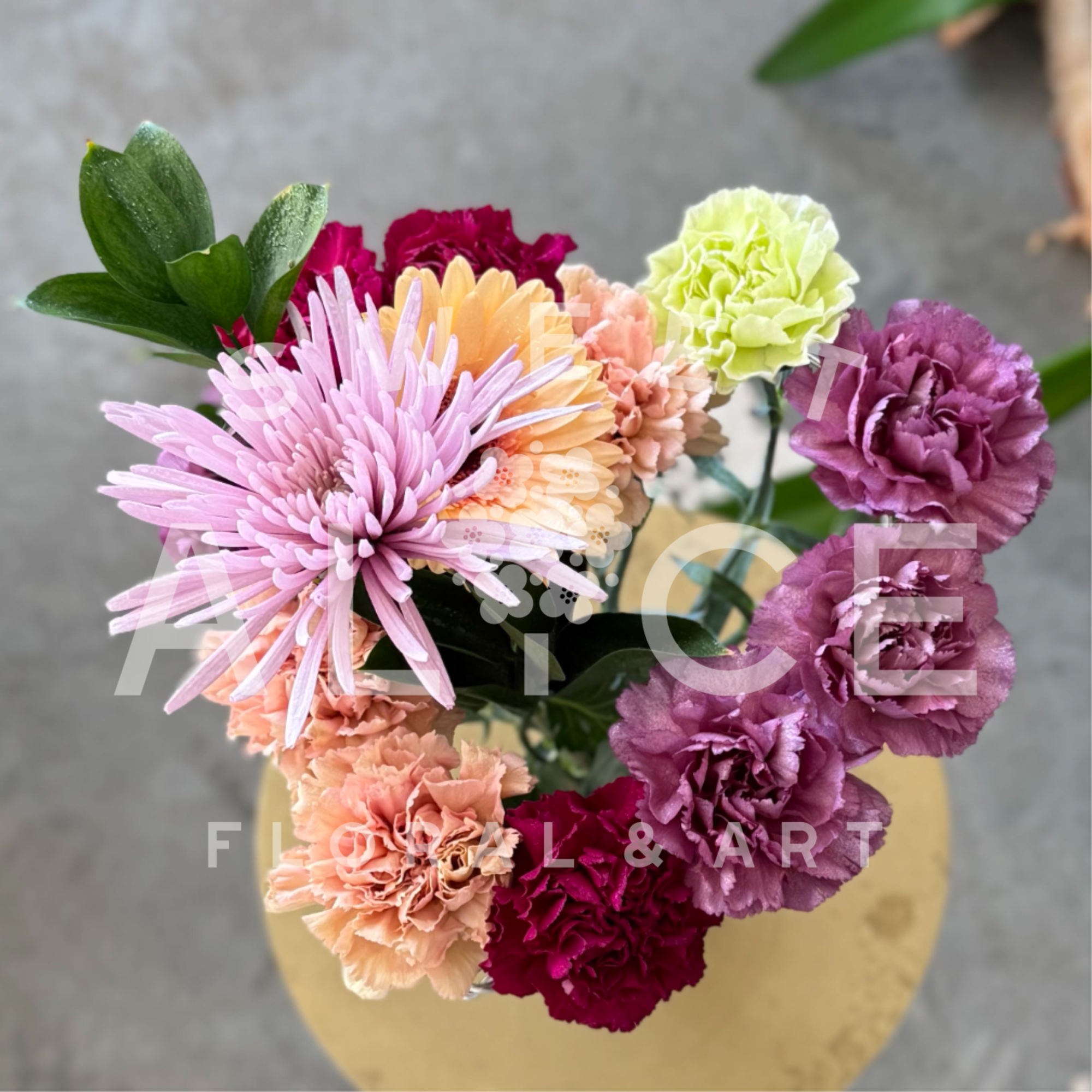 Carnations are skillfully arranged into a heart shape, accented with a gerbera