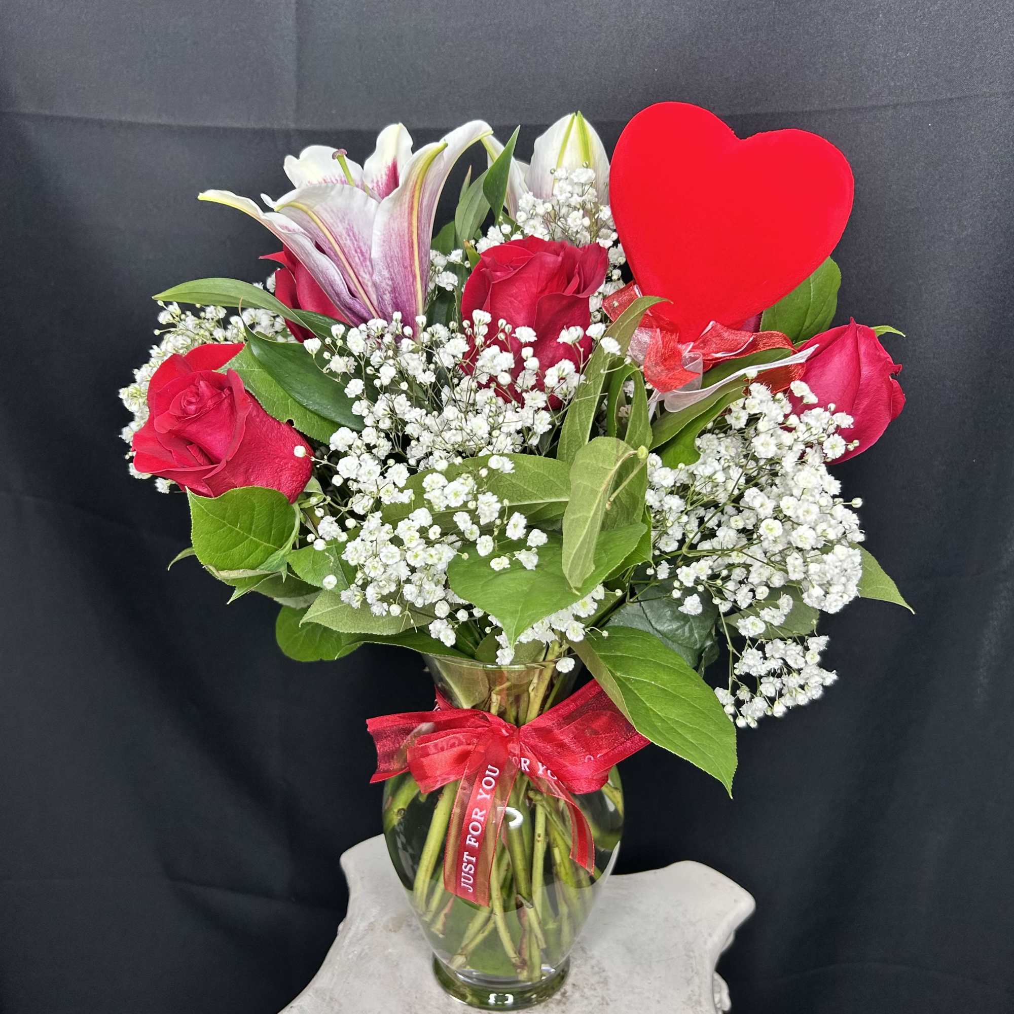 A medium-sized arrangement featuring 6 red roses, greenery, and baby's breath, accessorized