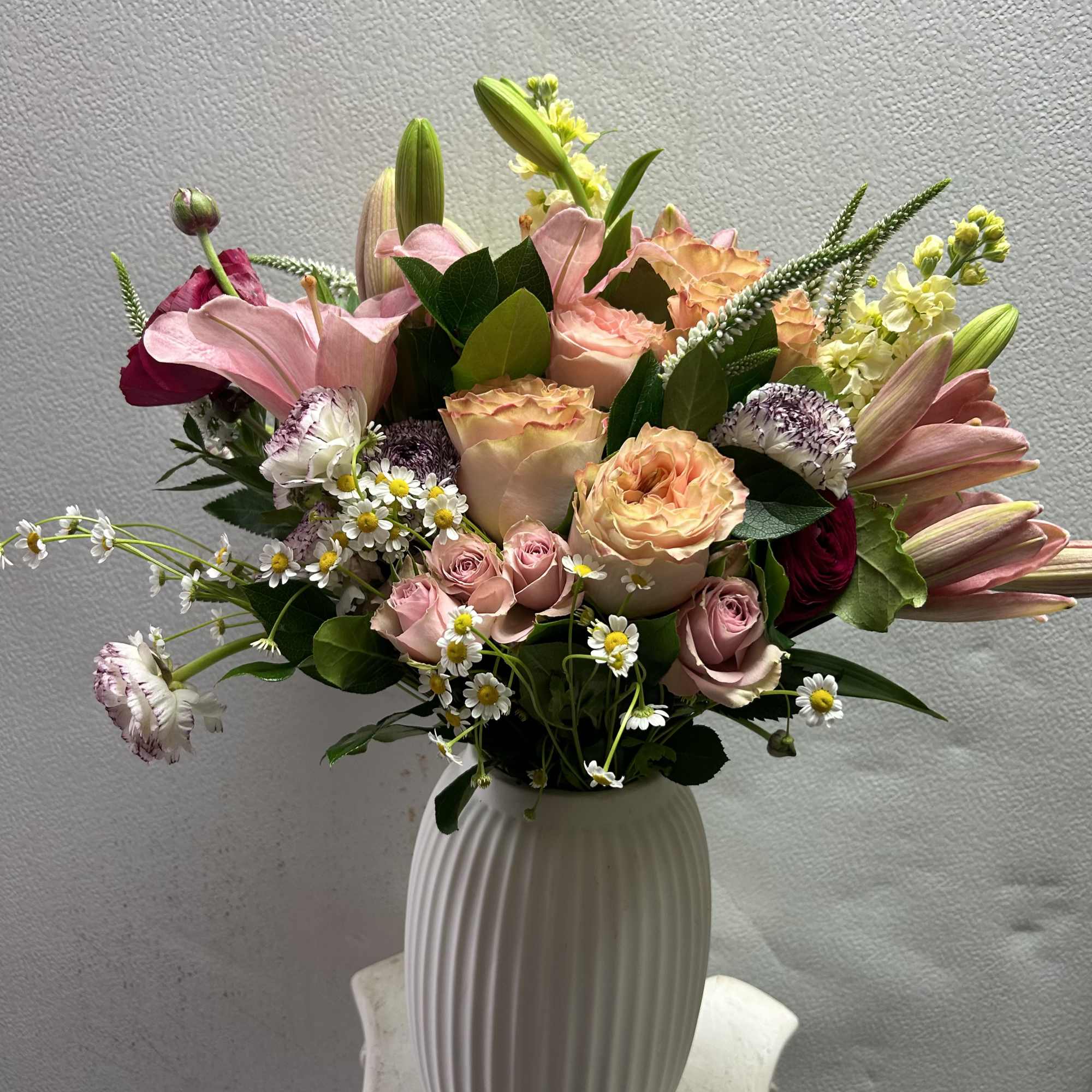 A mix of delicate spring flowers beautifully arranged in a matt white