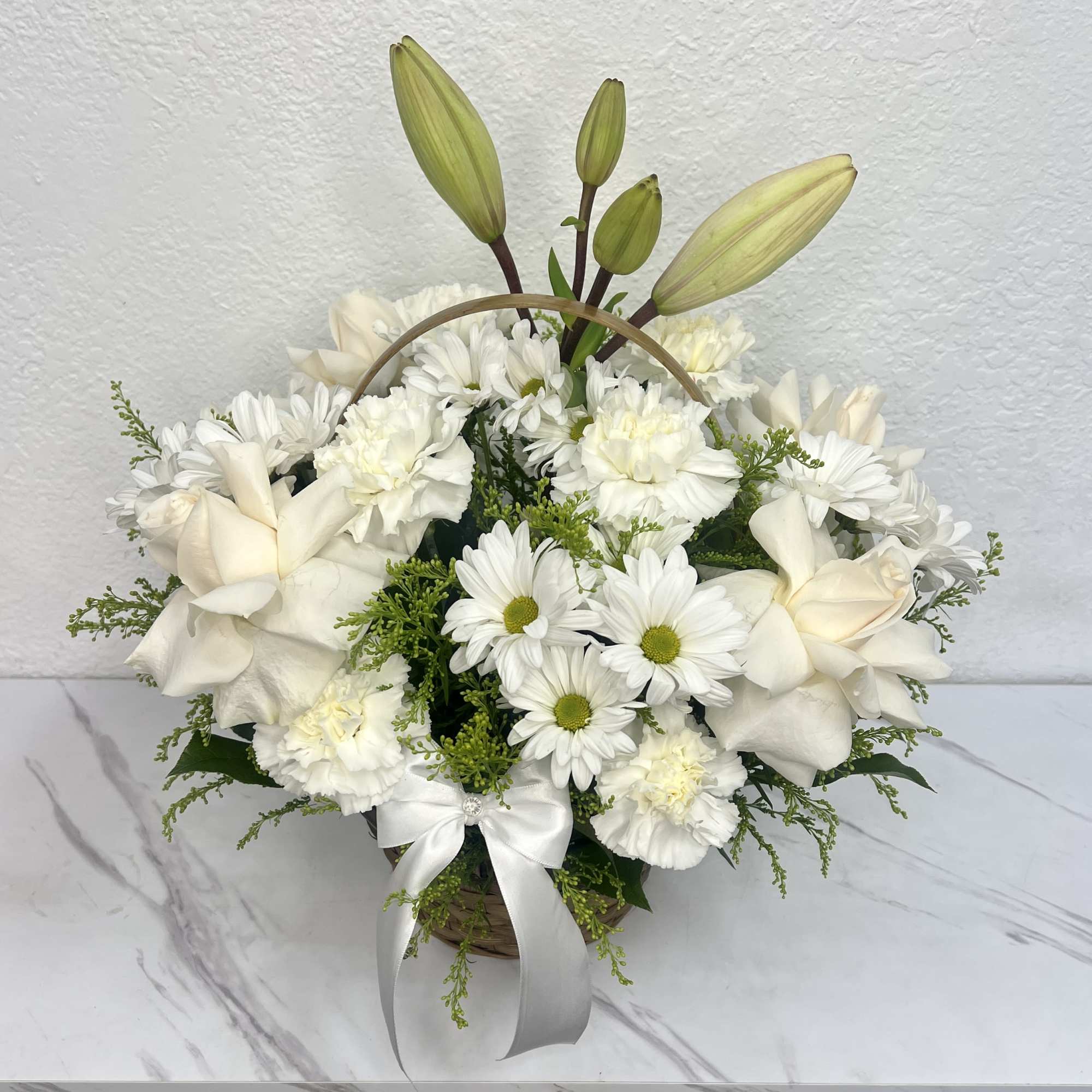 Buyer will receive a Basket with white roses, Lilly, carnations, and daisies.