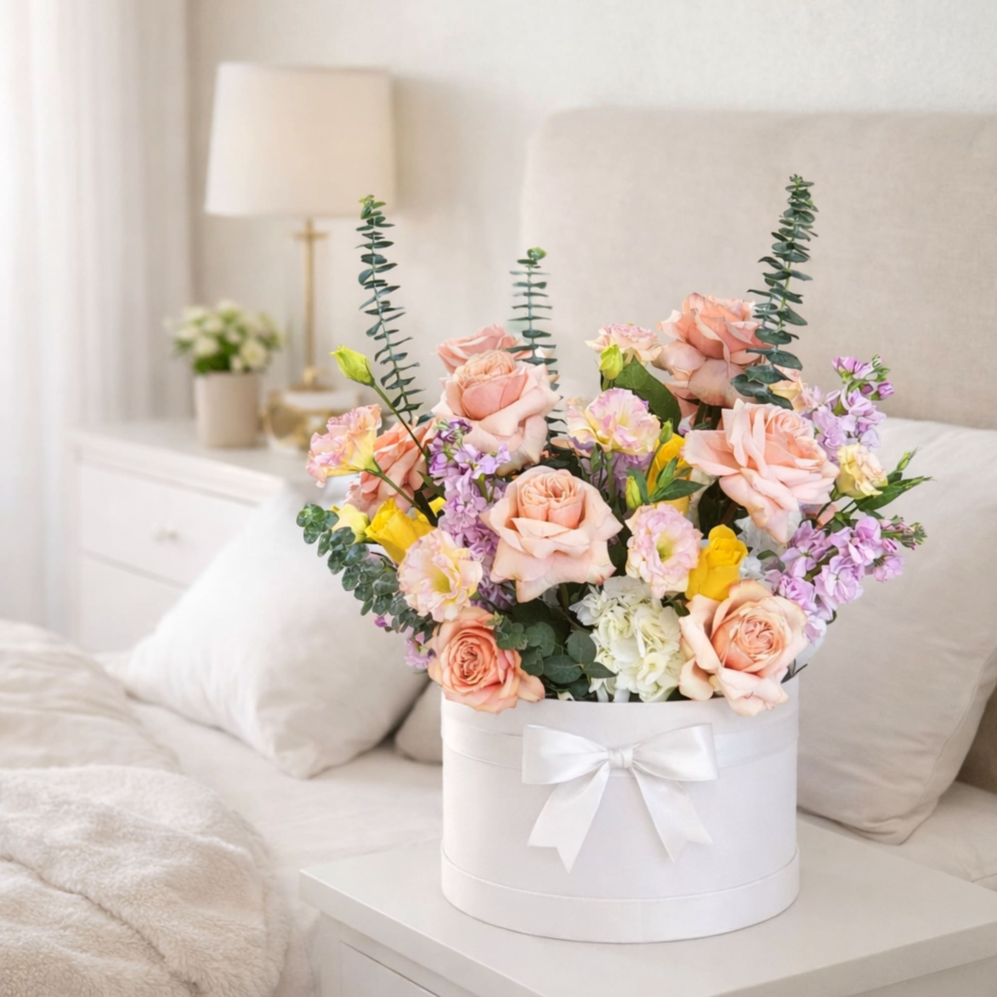 An elegant arrangement of blush roses, soft pastels, and fresh greenery in