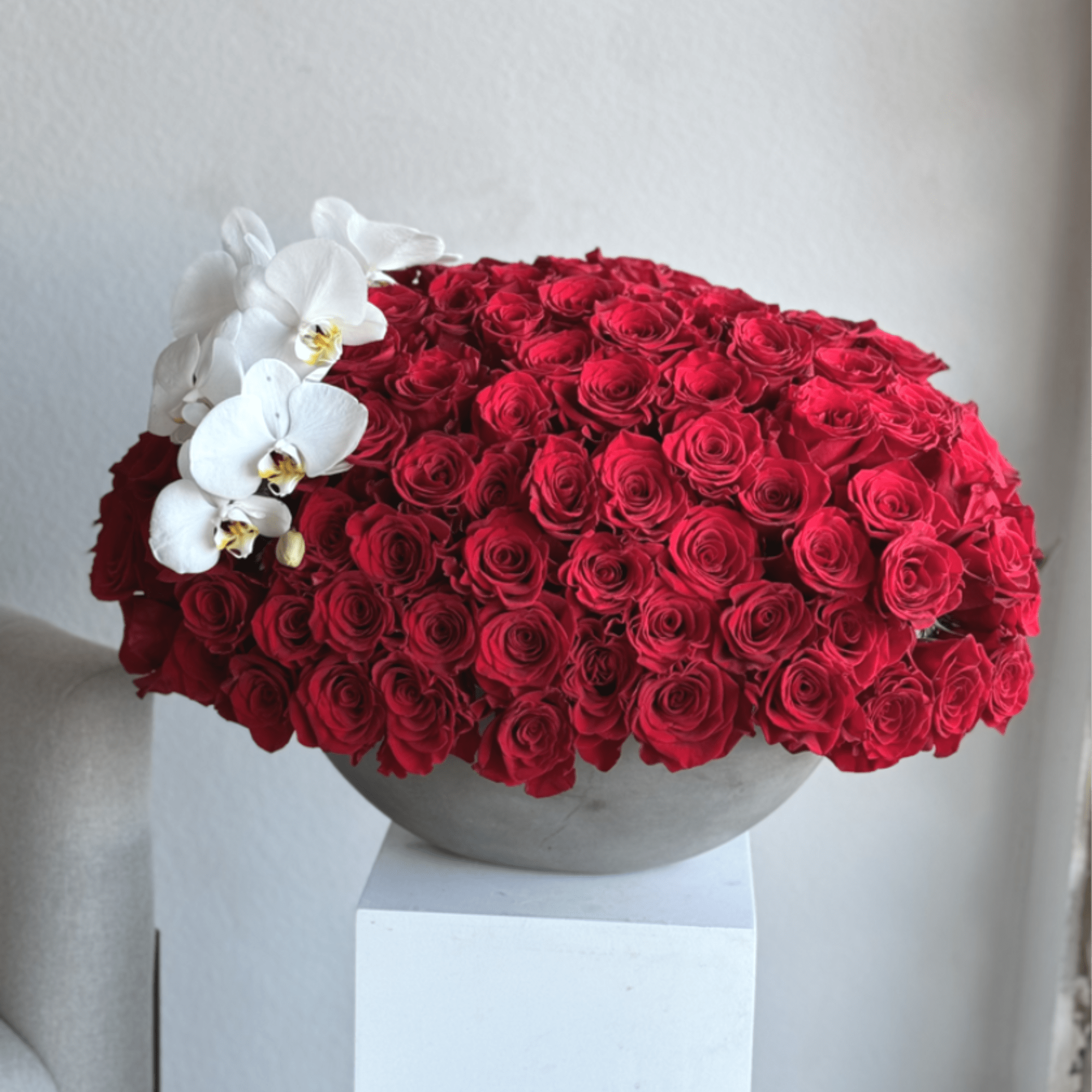 An opulent bouquet of 100 radiant red roses, beautifully arranged in a