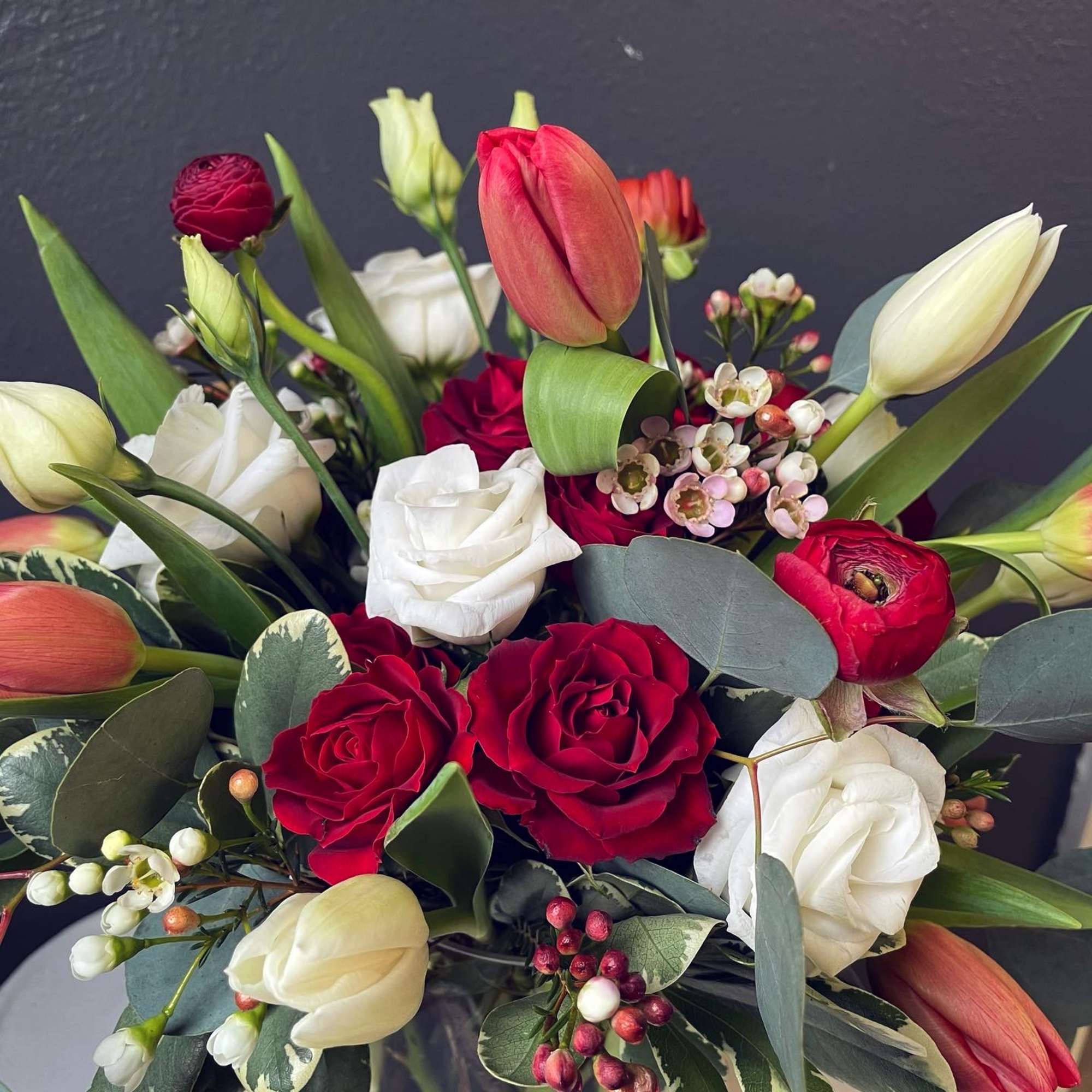 Tulips + red spray roses + red ranunculus + white lisianthus arranged