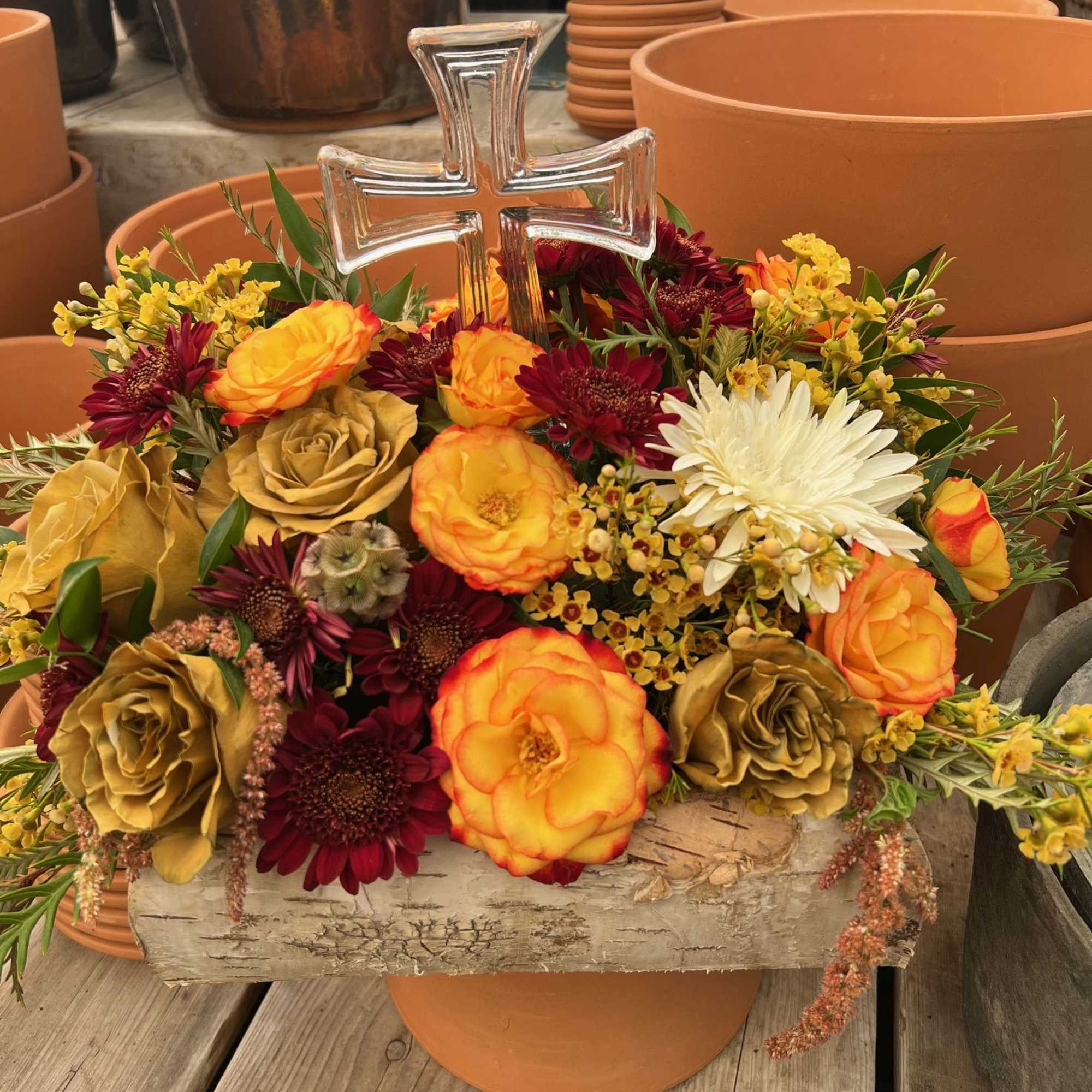 Honor a loved one with a mix of blooms and crystal cross.