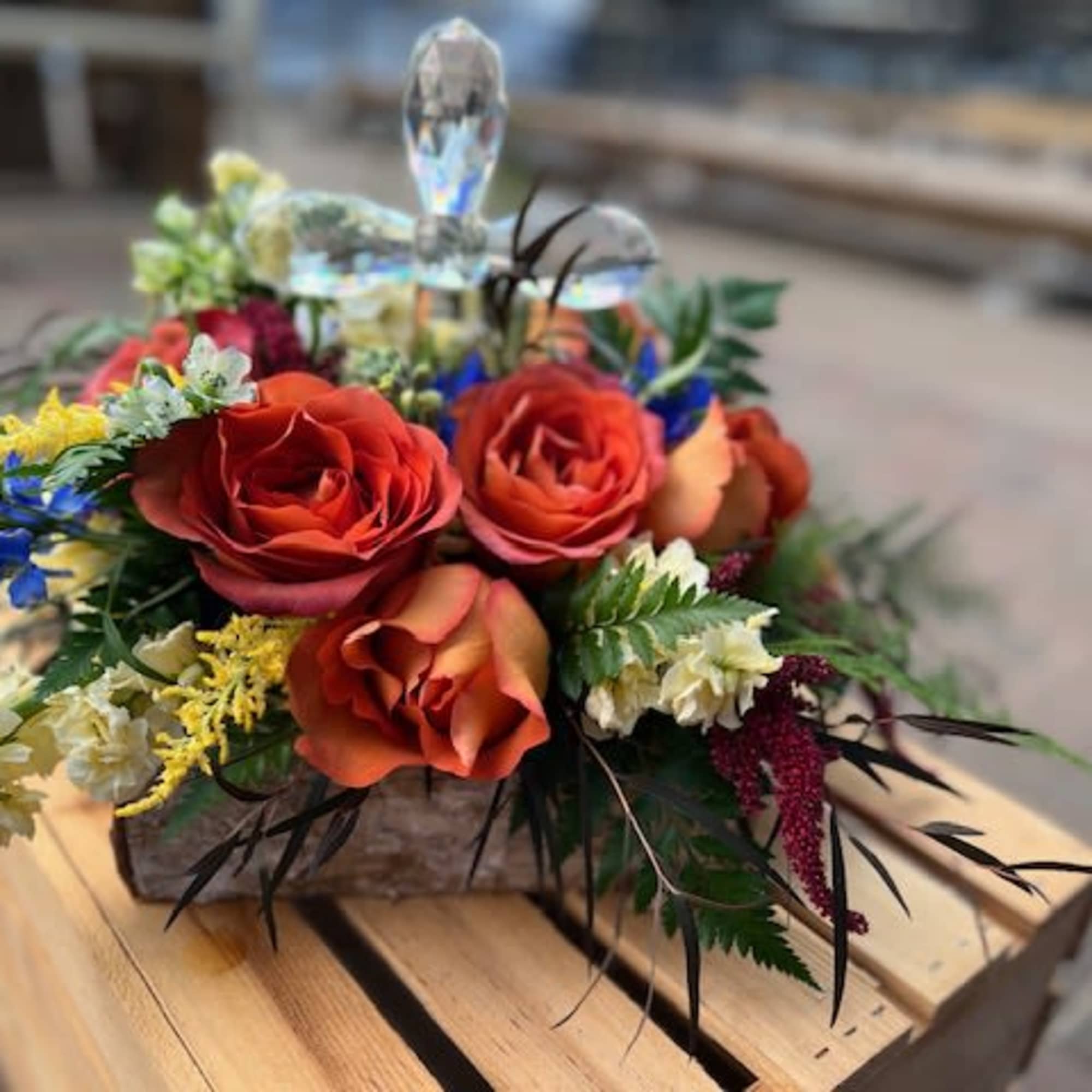 Honor a loved one with a mix of blooms and crystal cross.