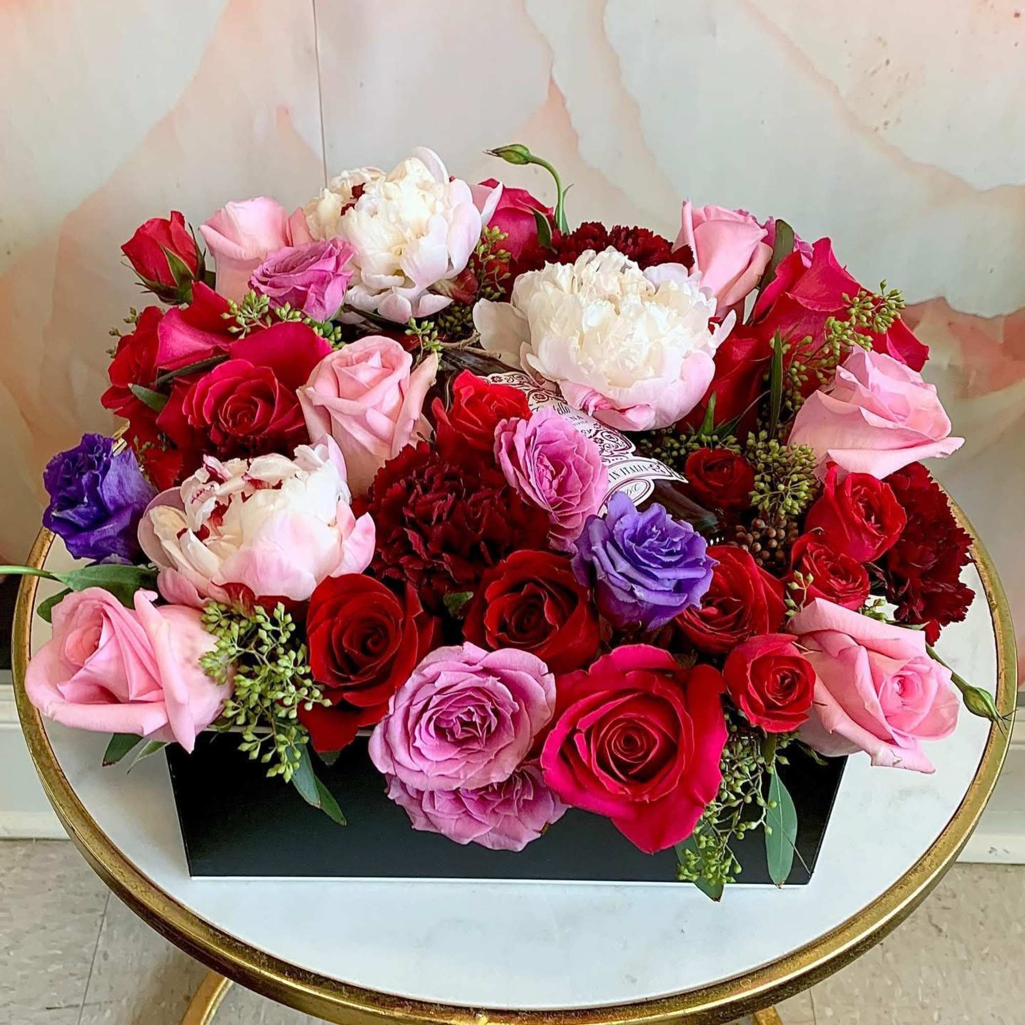 A large lush, garden-style arrangement featuring premium red and blush roses, soft