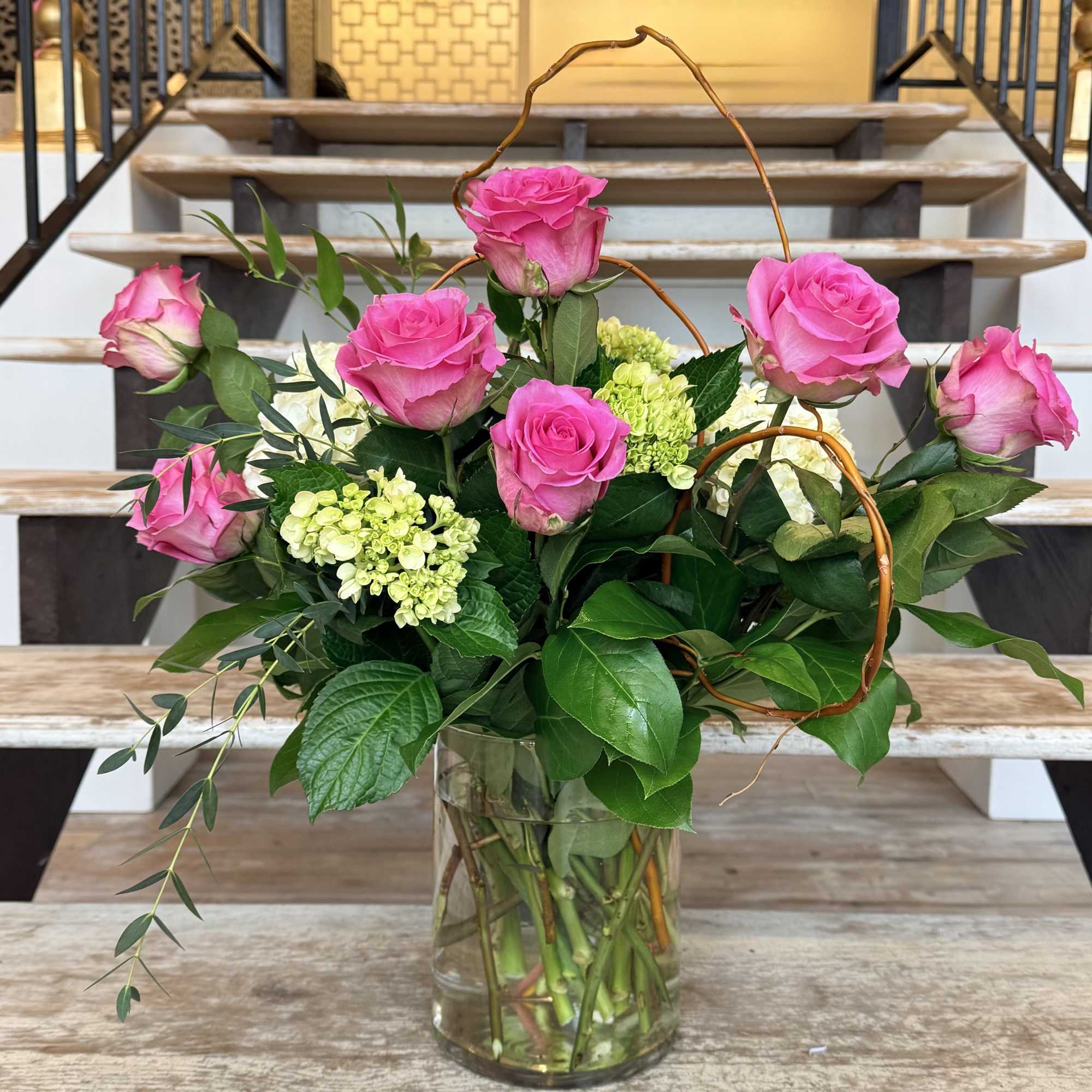 Pink Roses, green Mini Hydrangeas and lush greenery with curly willow accents.
