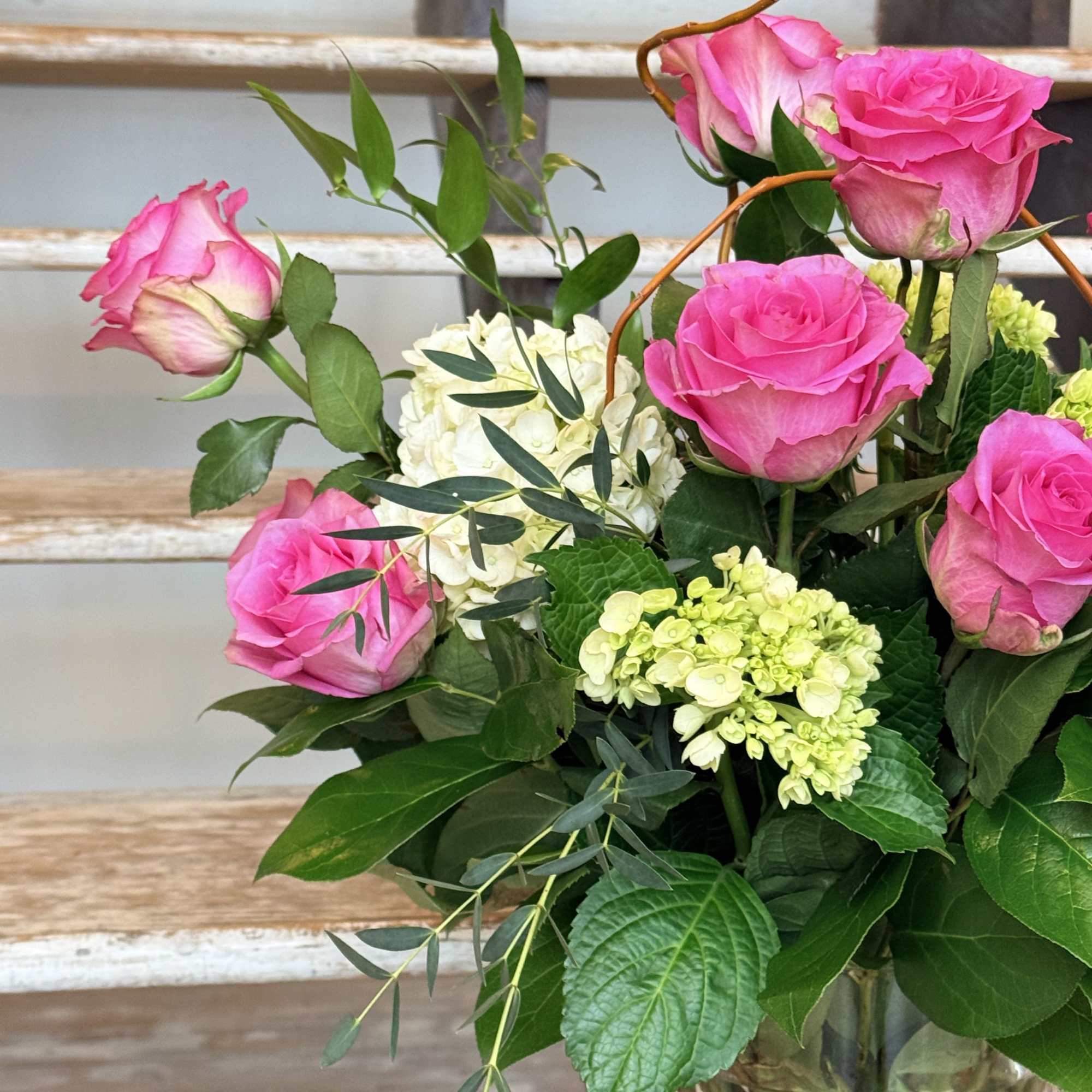 Pink Roses, green Mini Hydrangeas and lush greenery with curly willow accents.