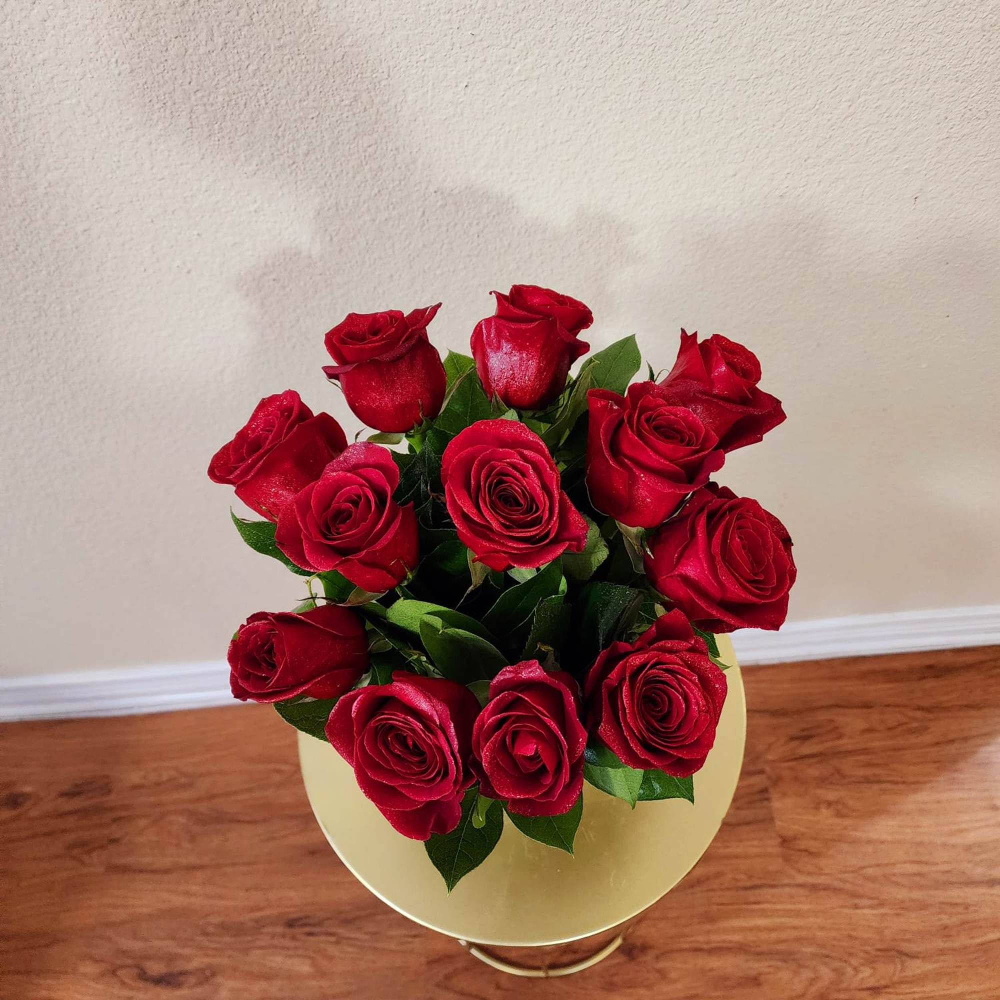 Roses in a clear vase with some greens in it, a classic