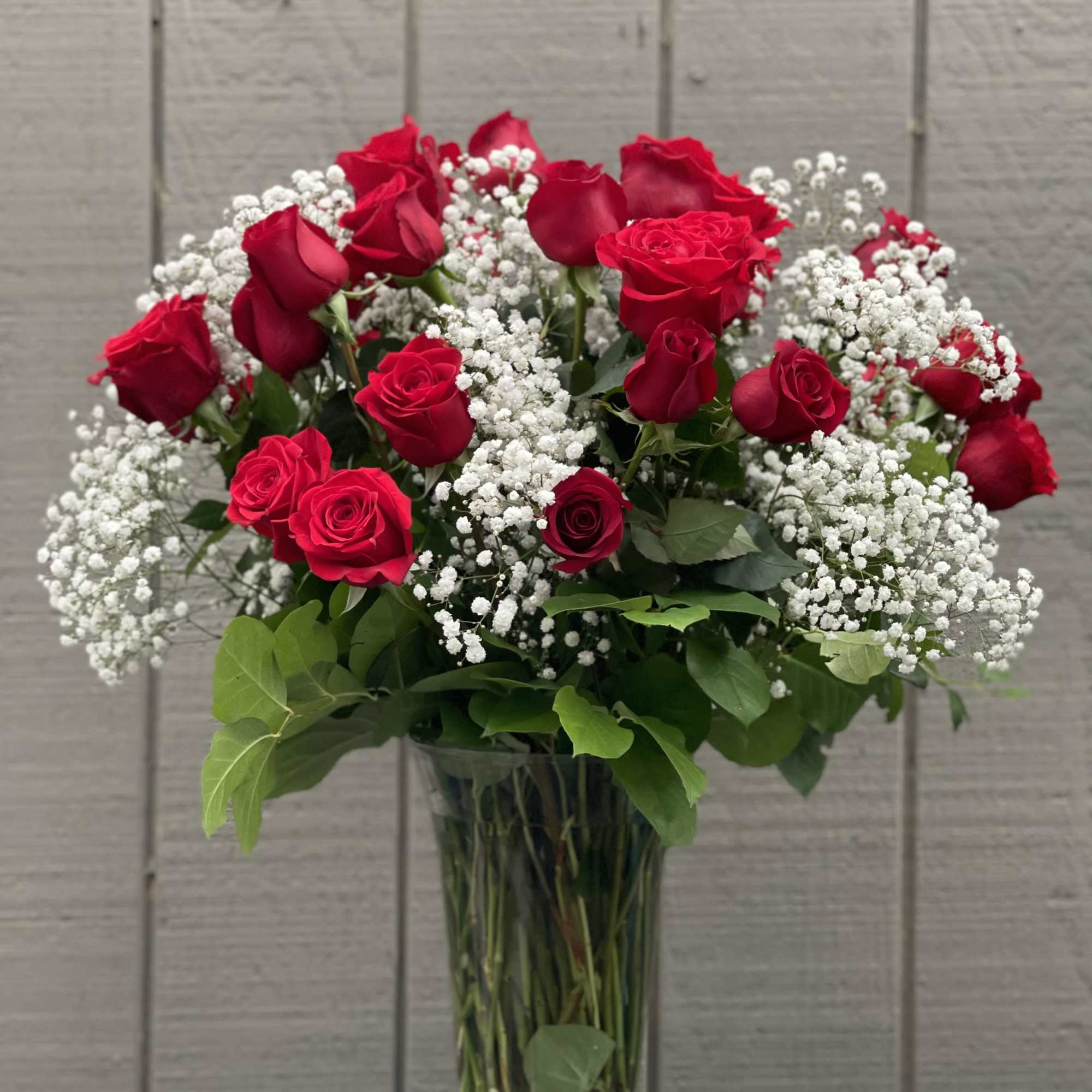 36 long stemmed red roses arranged in a vase with baby's breath