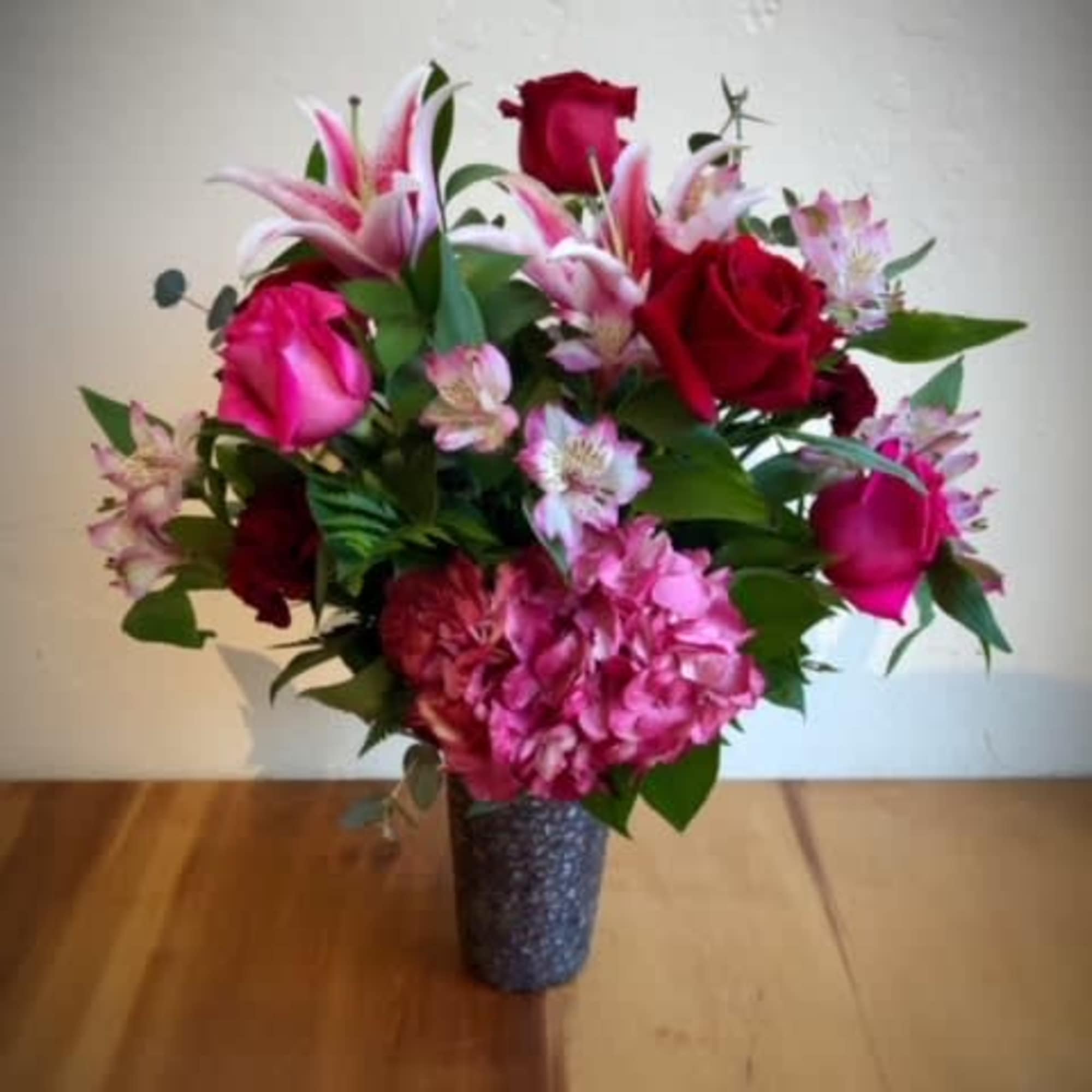 This romantic vase is filled with red roses, hot pink roses, pink