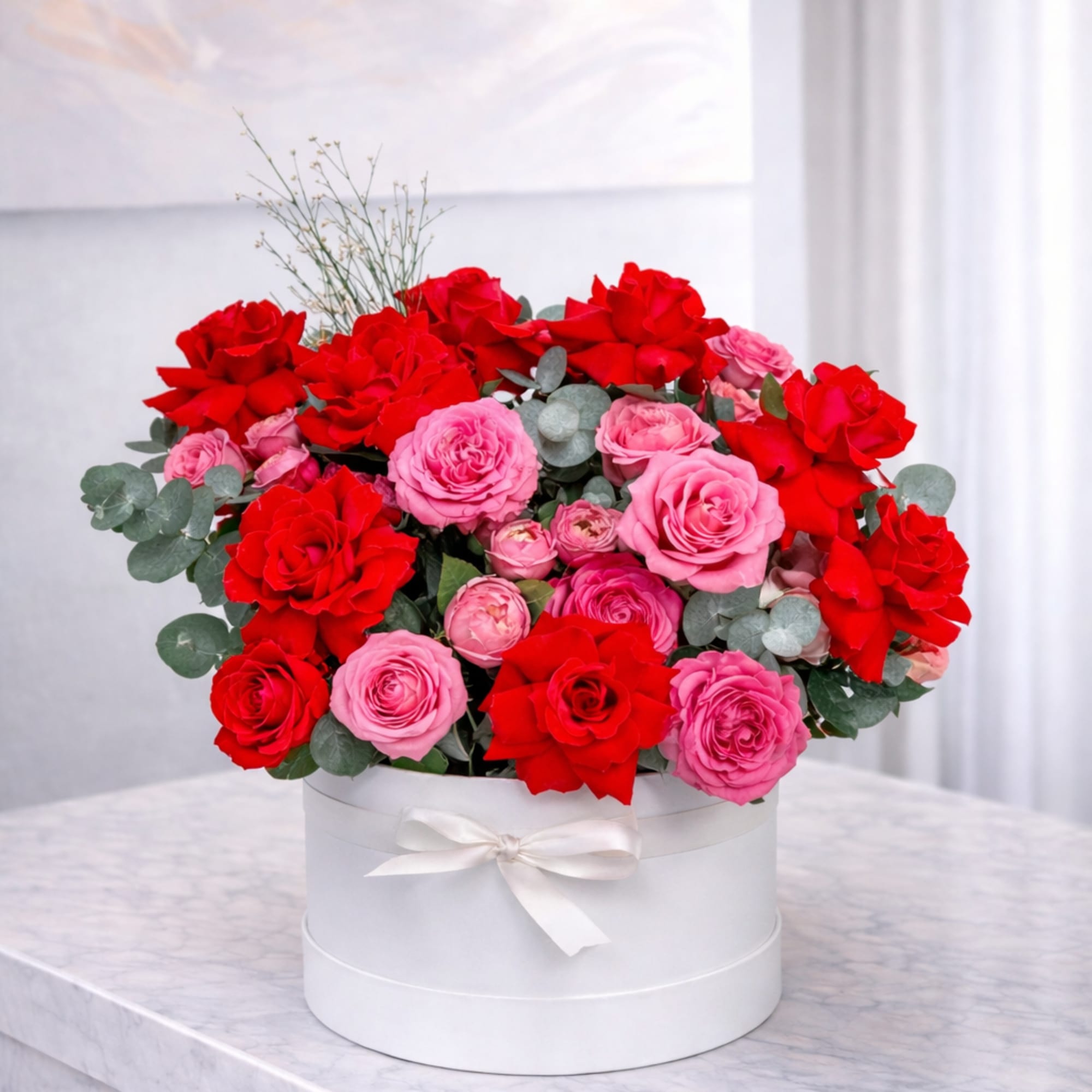 A luxurious arrangement of fresh red and pink roses designed in an