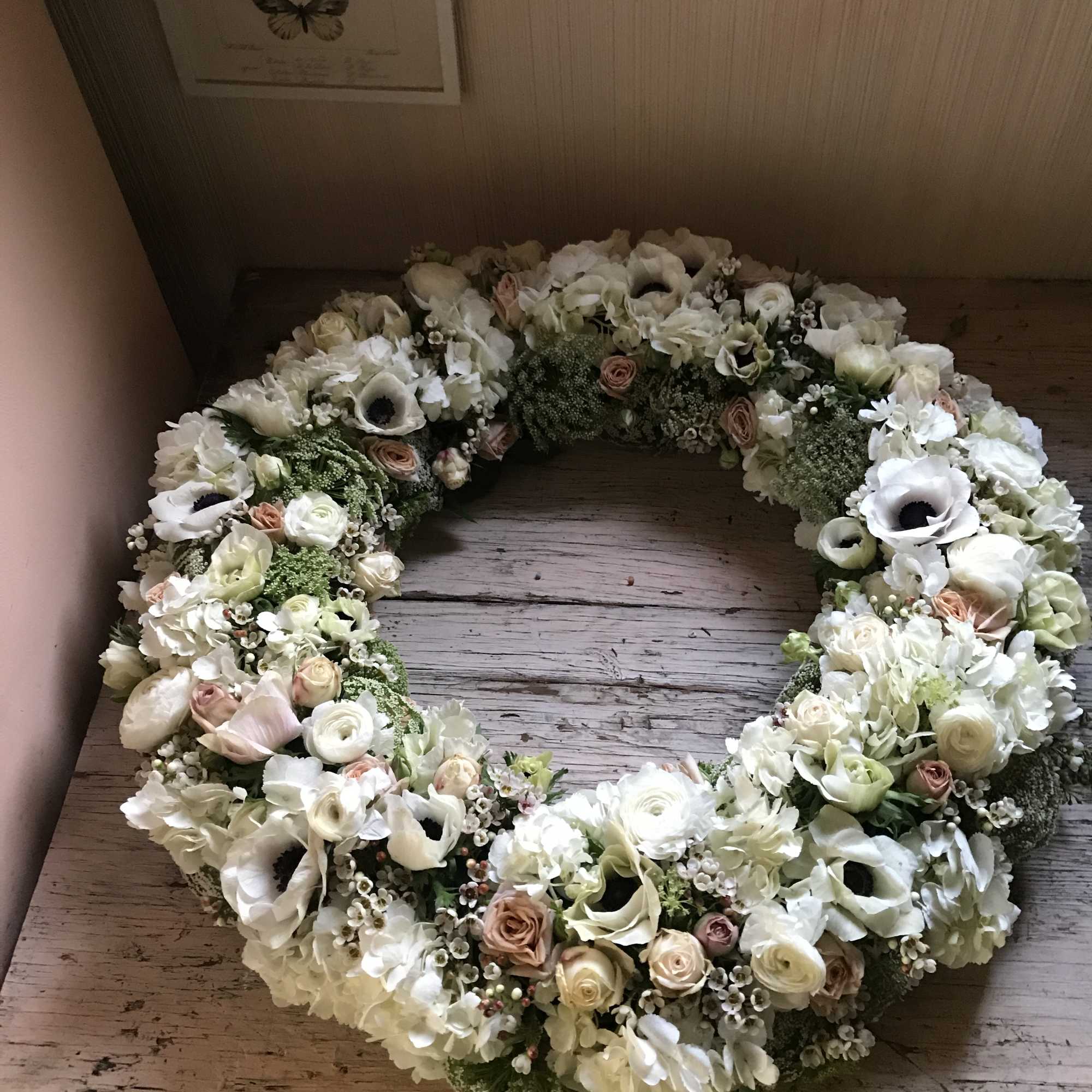 Beautiful wreath of fresh flowers in all white colors. Roses, anemones, ranunculus