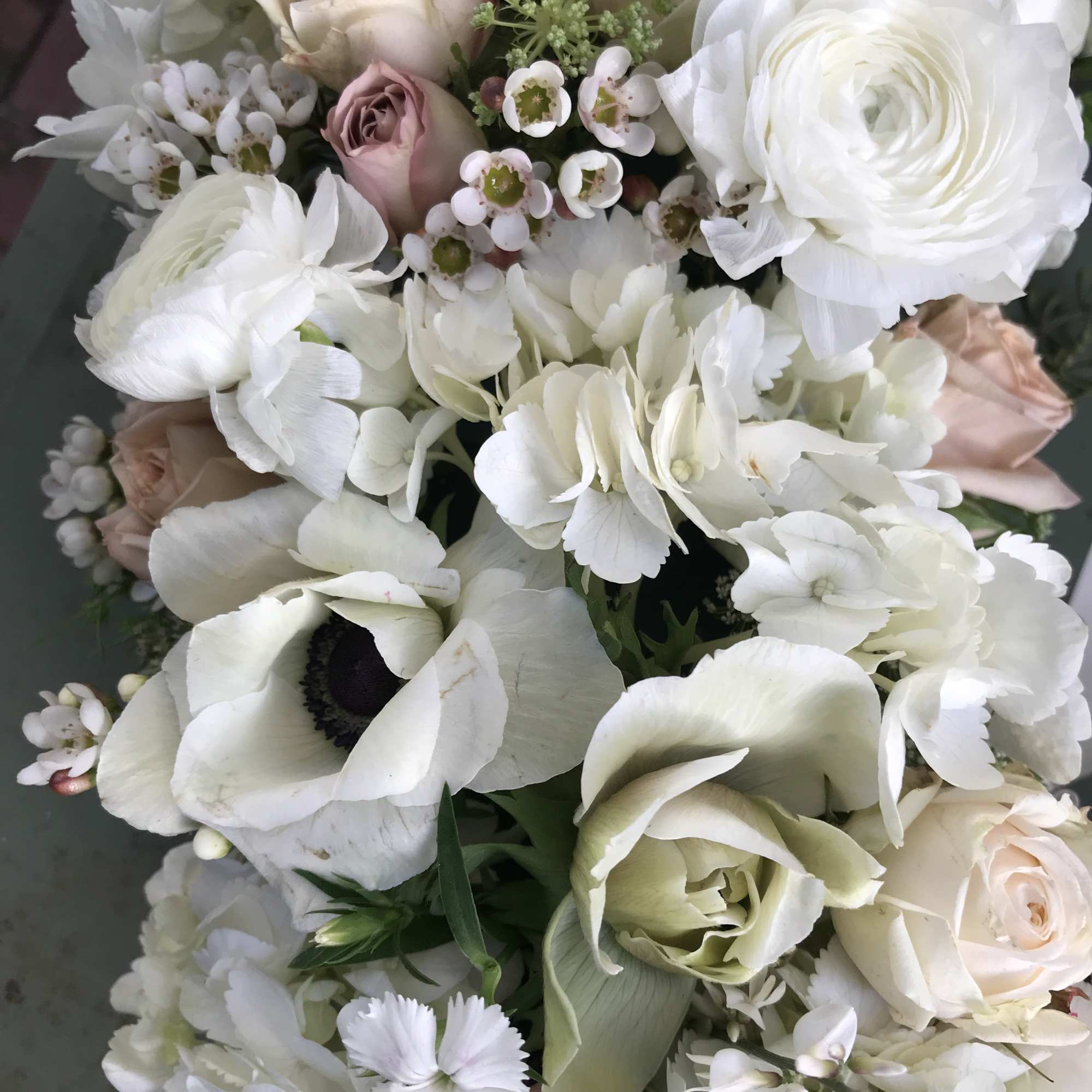 Beautiful wreath of fresh flowers in all white colors. Roses, anemones, ranunculus