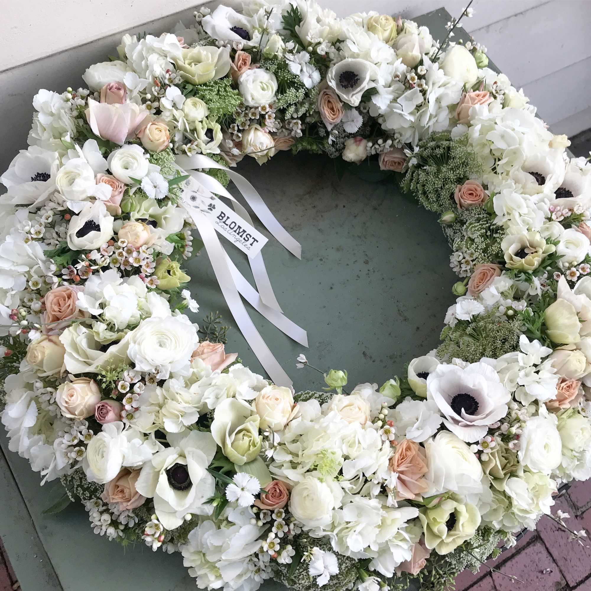 Beautiful wreath of fresh flowers in all white colors. Roses, anemones, ranunculus