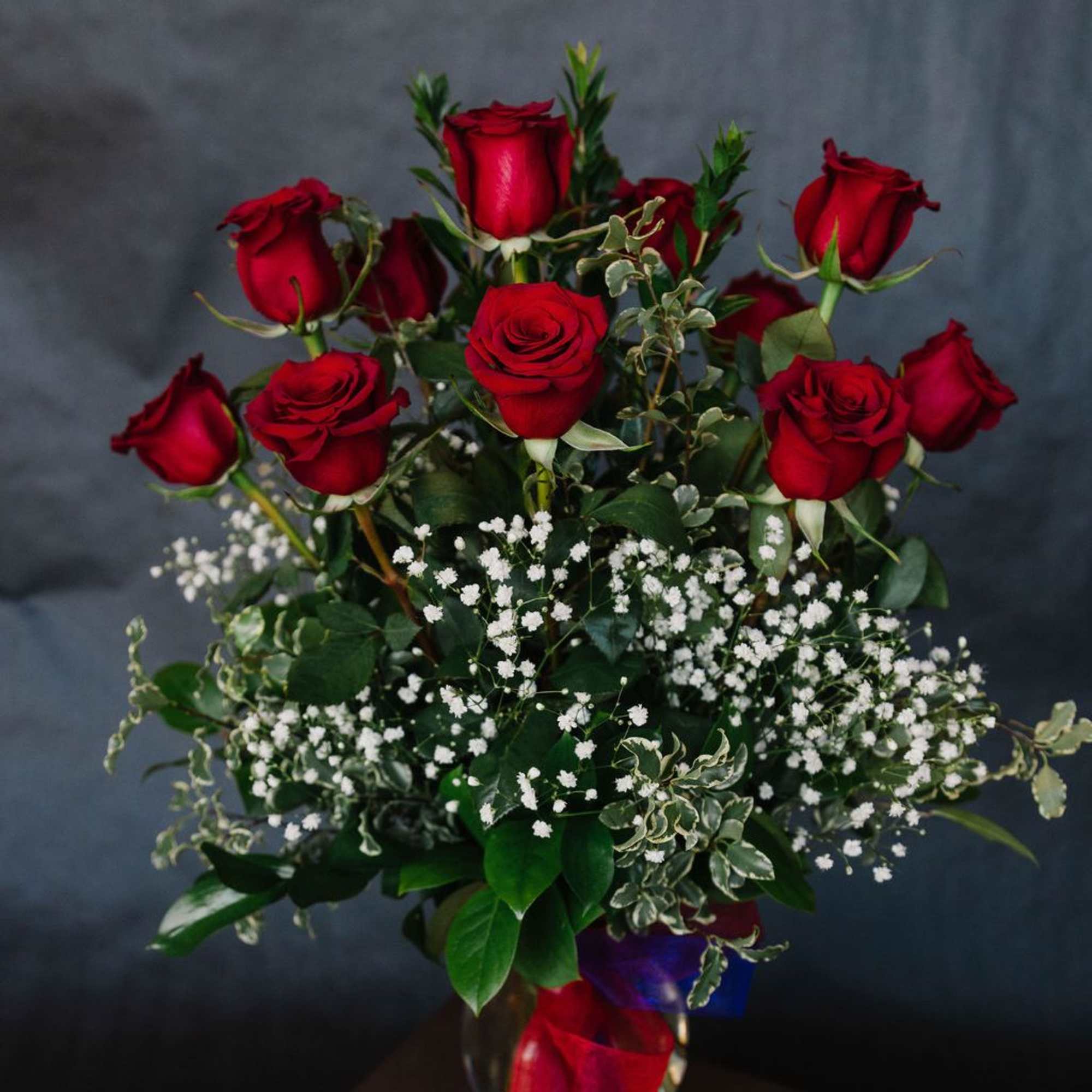 12 beautiful, velvety red roses designed in a vase with premium greenery
