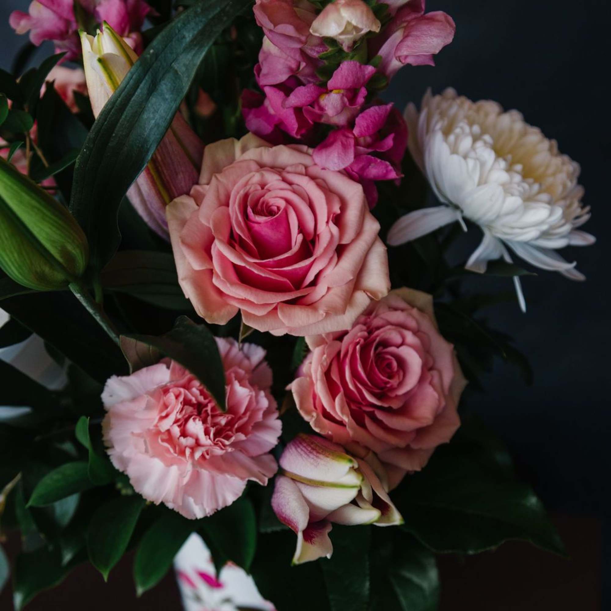 An elegant Valentine arrangement featuring layered pink roses, snapdragons, lilies, and fresh