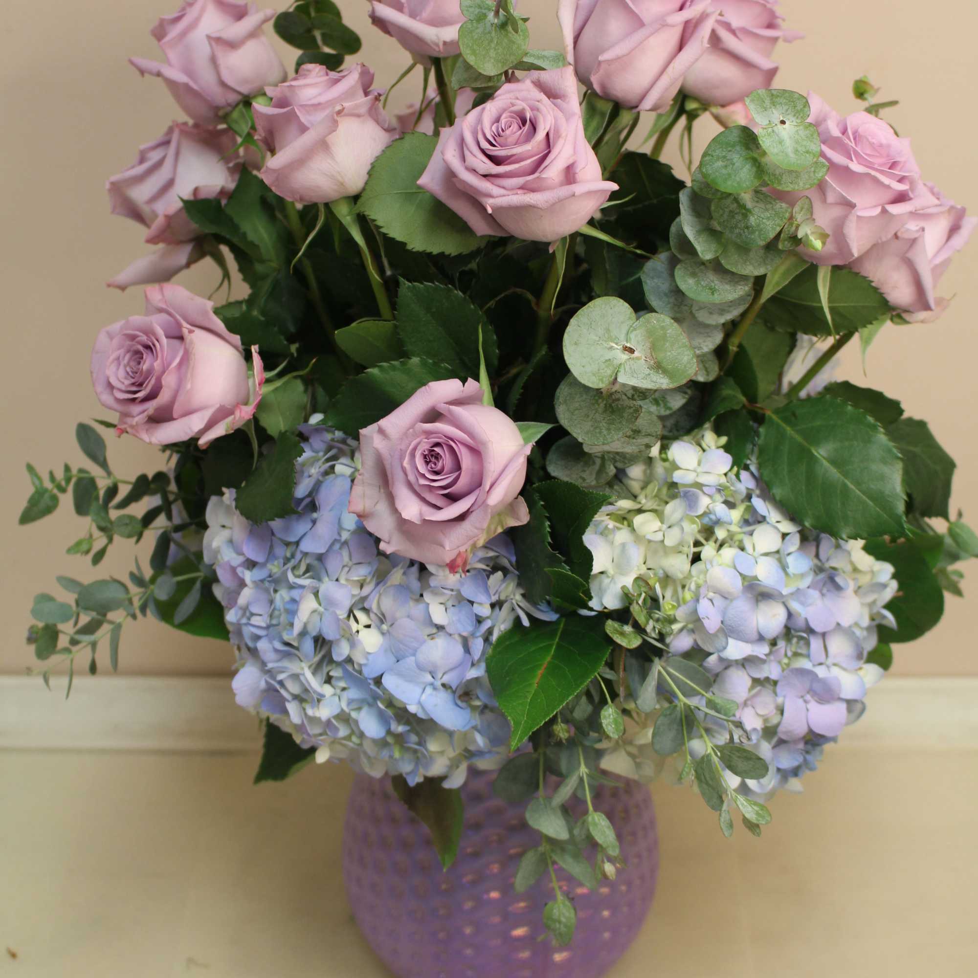 A purple hobnail vase holds a dozen lavender (Ocean Song), adorned with
