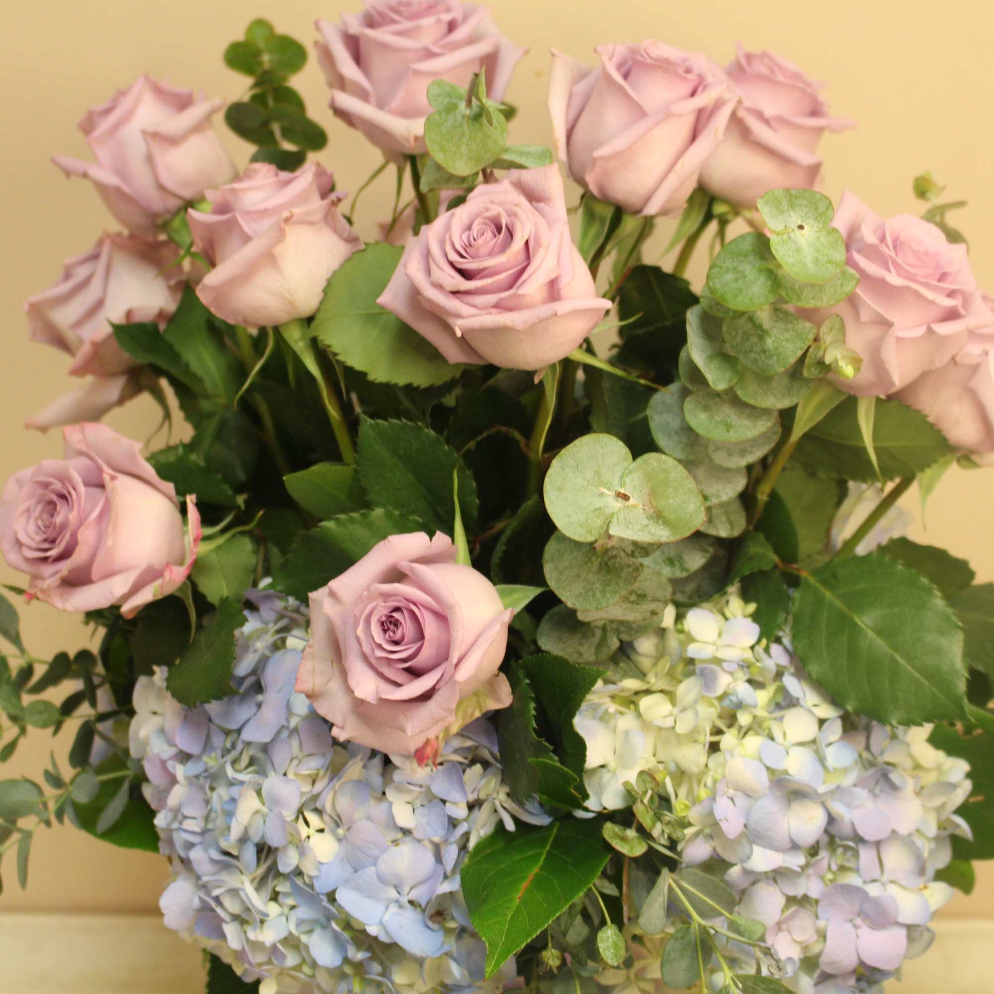 A purple hobnail vase holds a dozen lavender (Ocean Song), adorned with