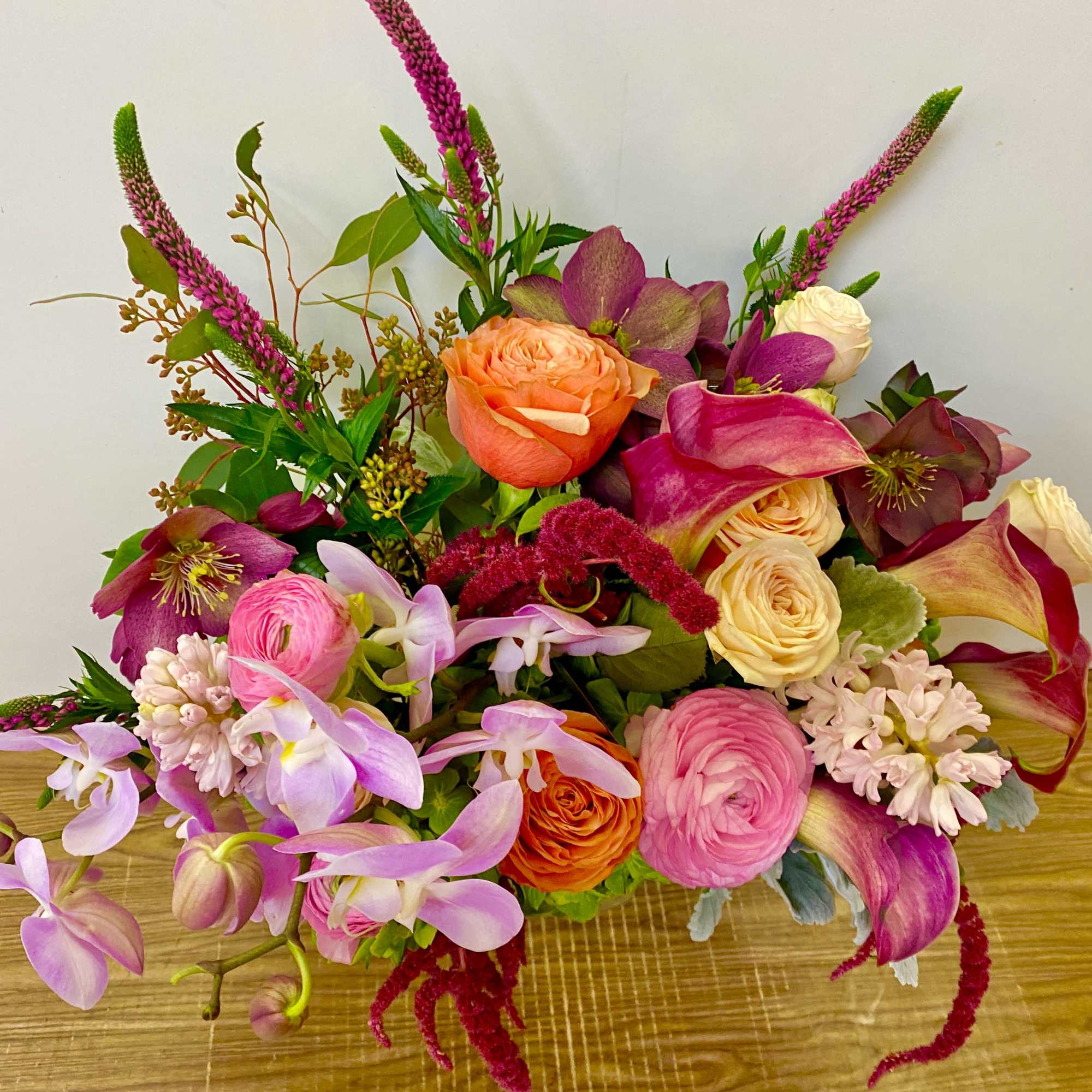 Combinations of purple, burgundy, orange flowers in a glass vase
