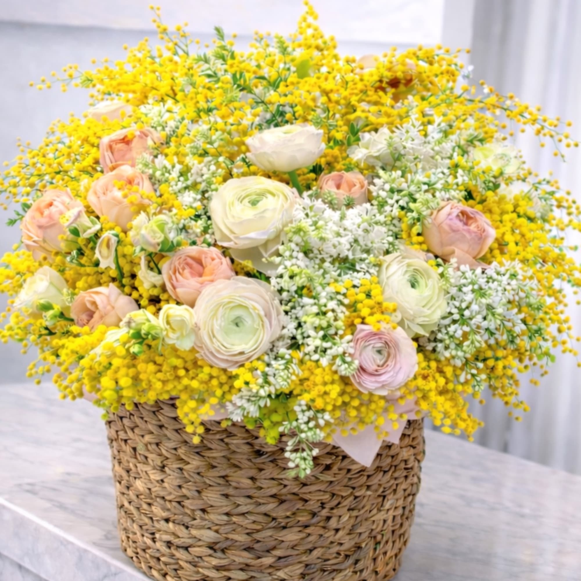 Delicate ranunculus, airy mimosa, and gentle pastel roses, handcrafted with care for