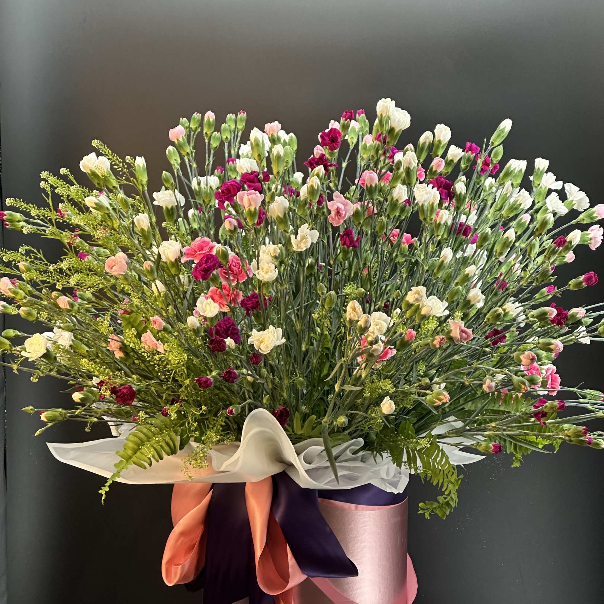 This arrangement is a full , mix carnation ,with greenery  garden