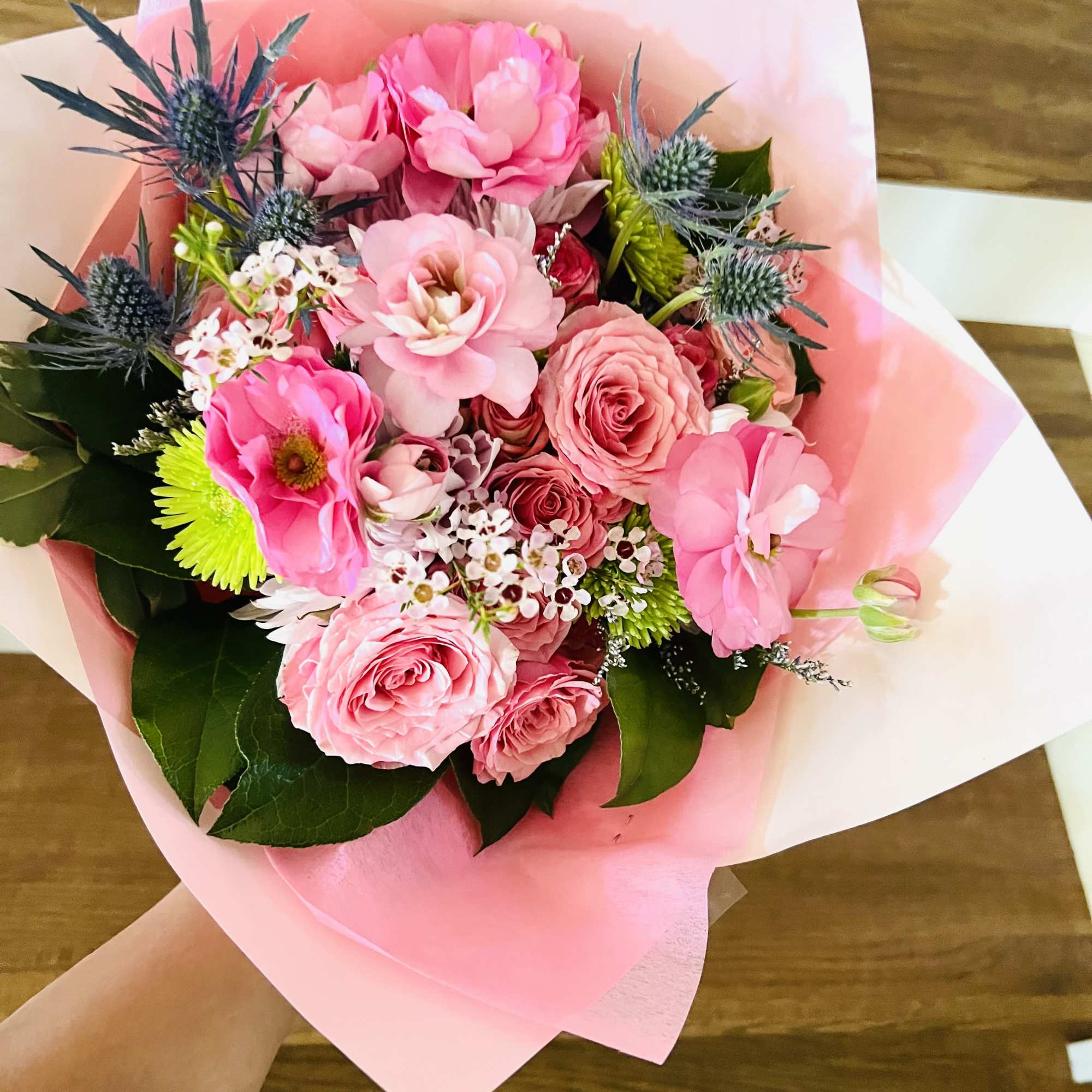 A designer&rsquo;s choice wrapped bouquet featuring 5 radiant roses paired with premium