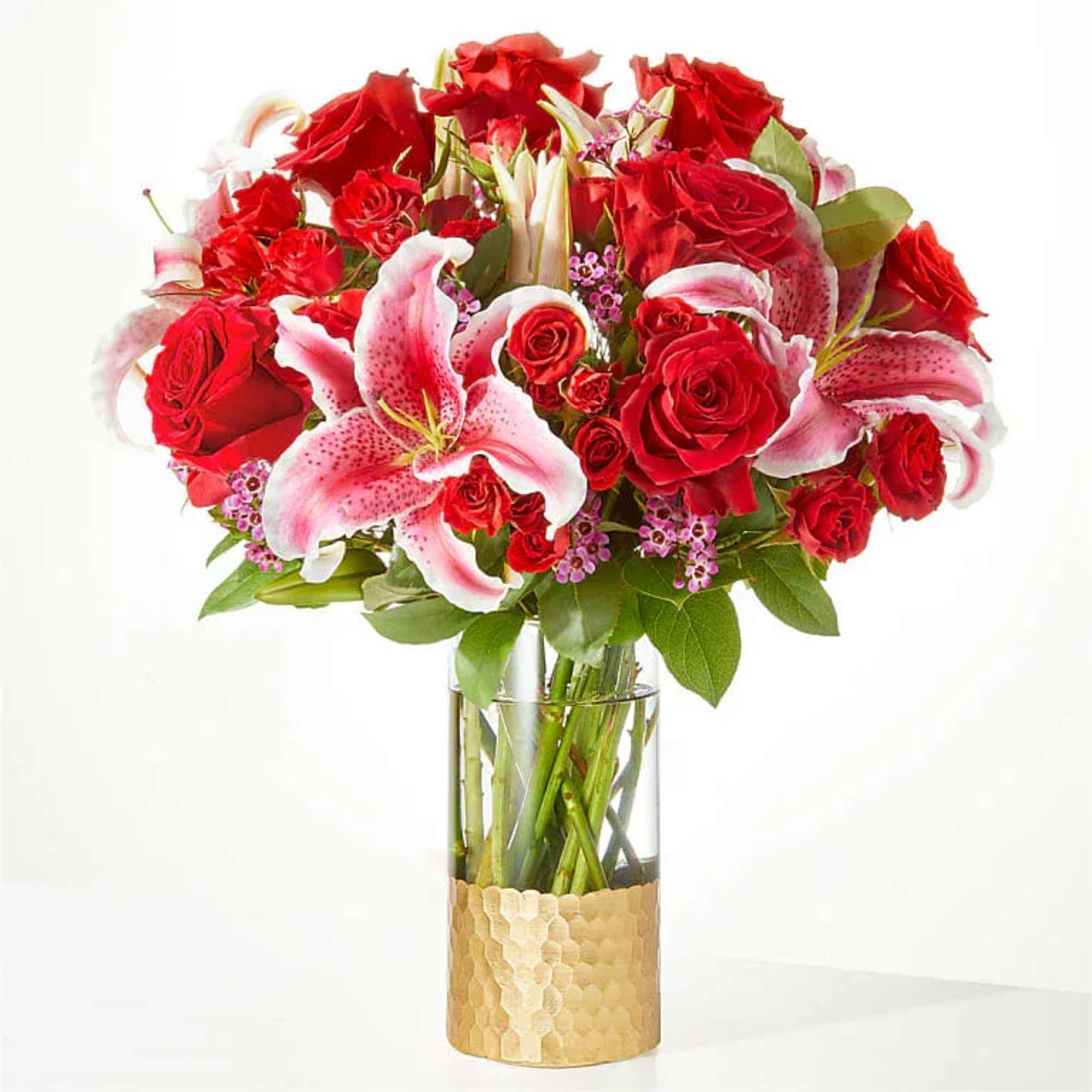 Blooming red roses, exquisite lilies, and accents of spray roses are expertly