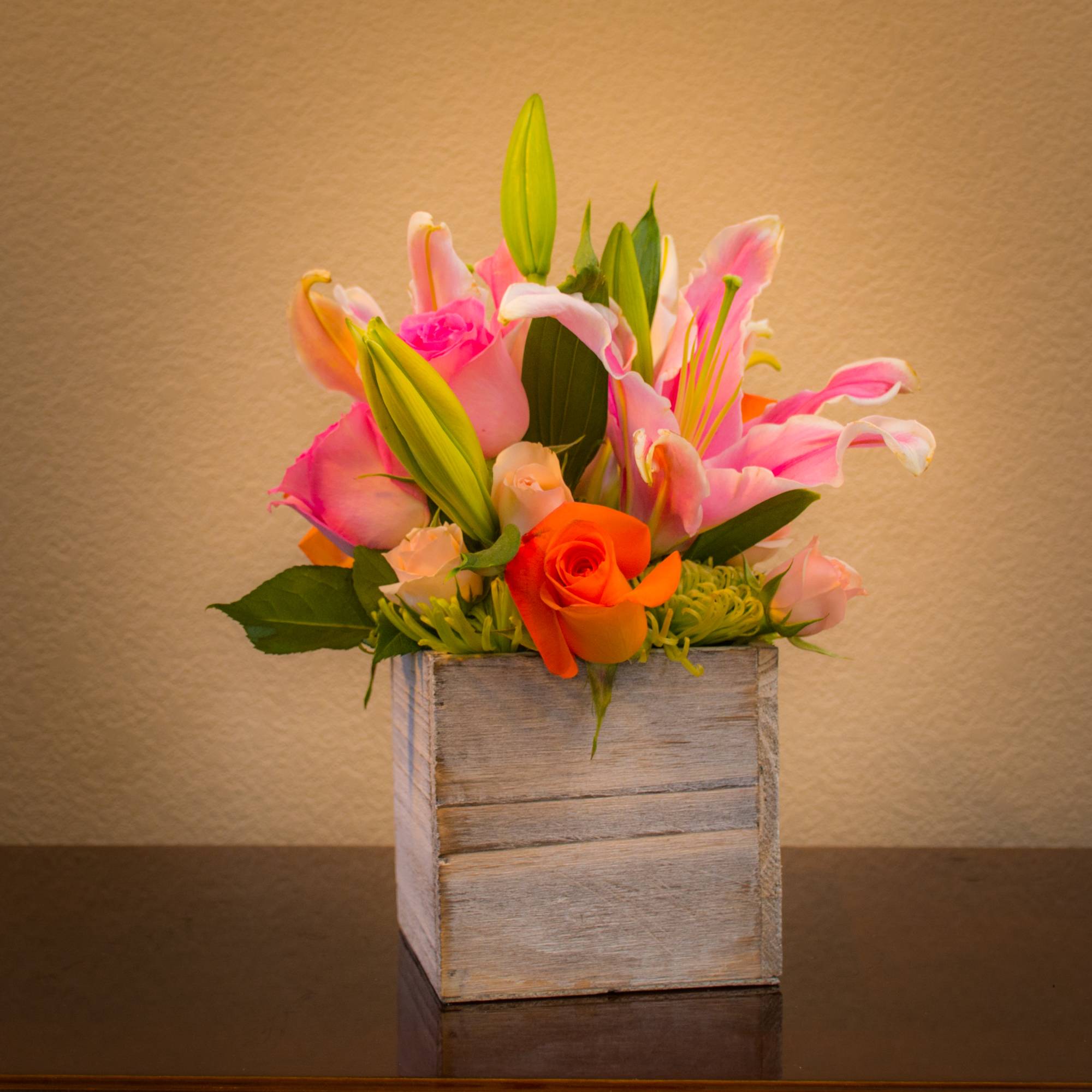 Lilies and roses on a bed of mums. Compact arrangement nice for