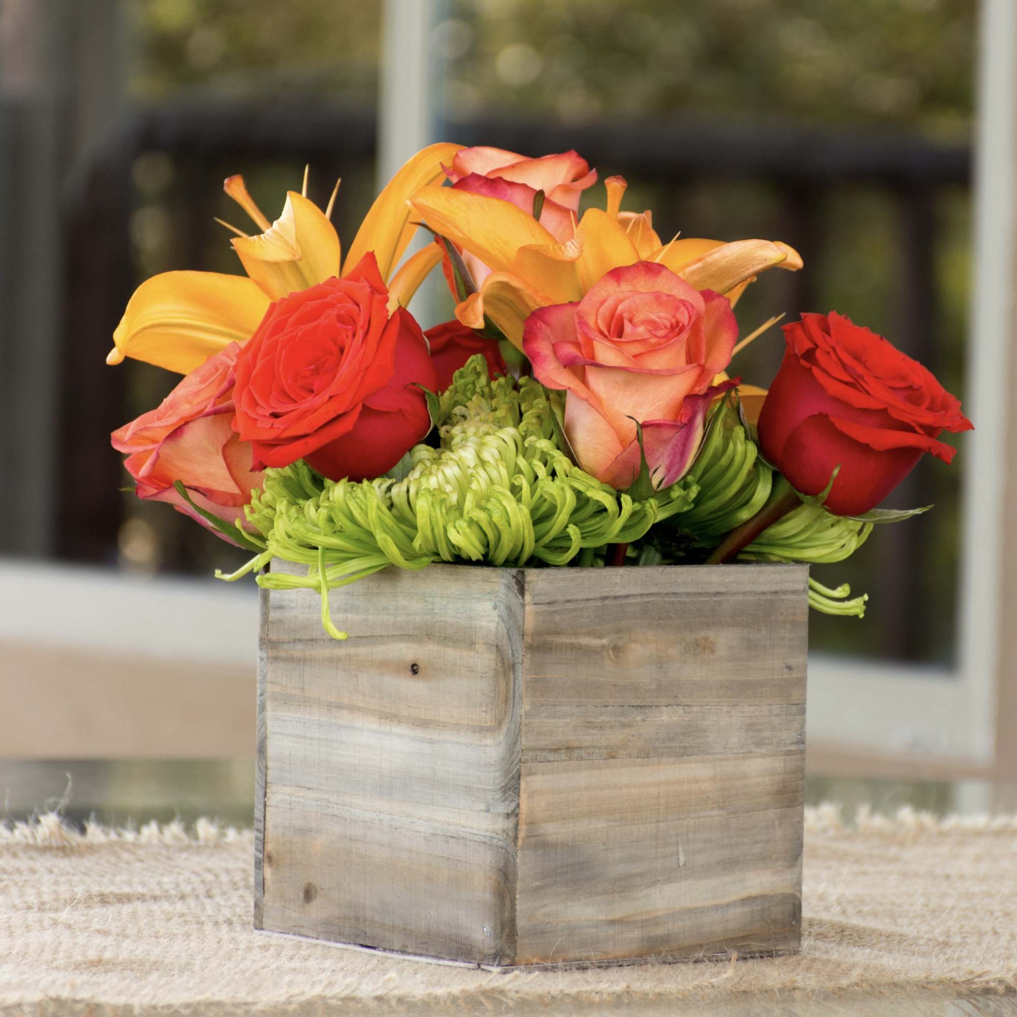 Lilies and roses on a bed of mums. Compact arrangement nice for
