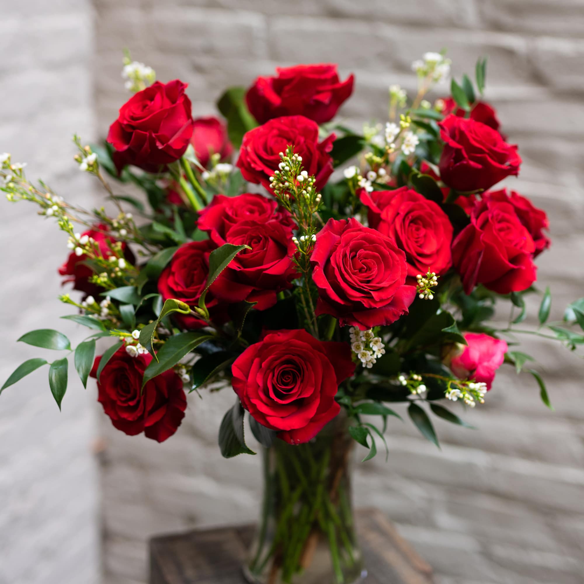 A classic arrangement of twelve long stemmed red roses with greens and