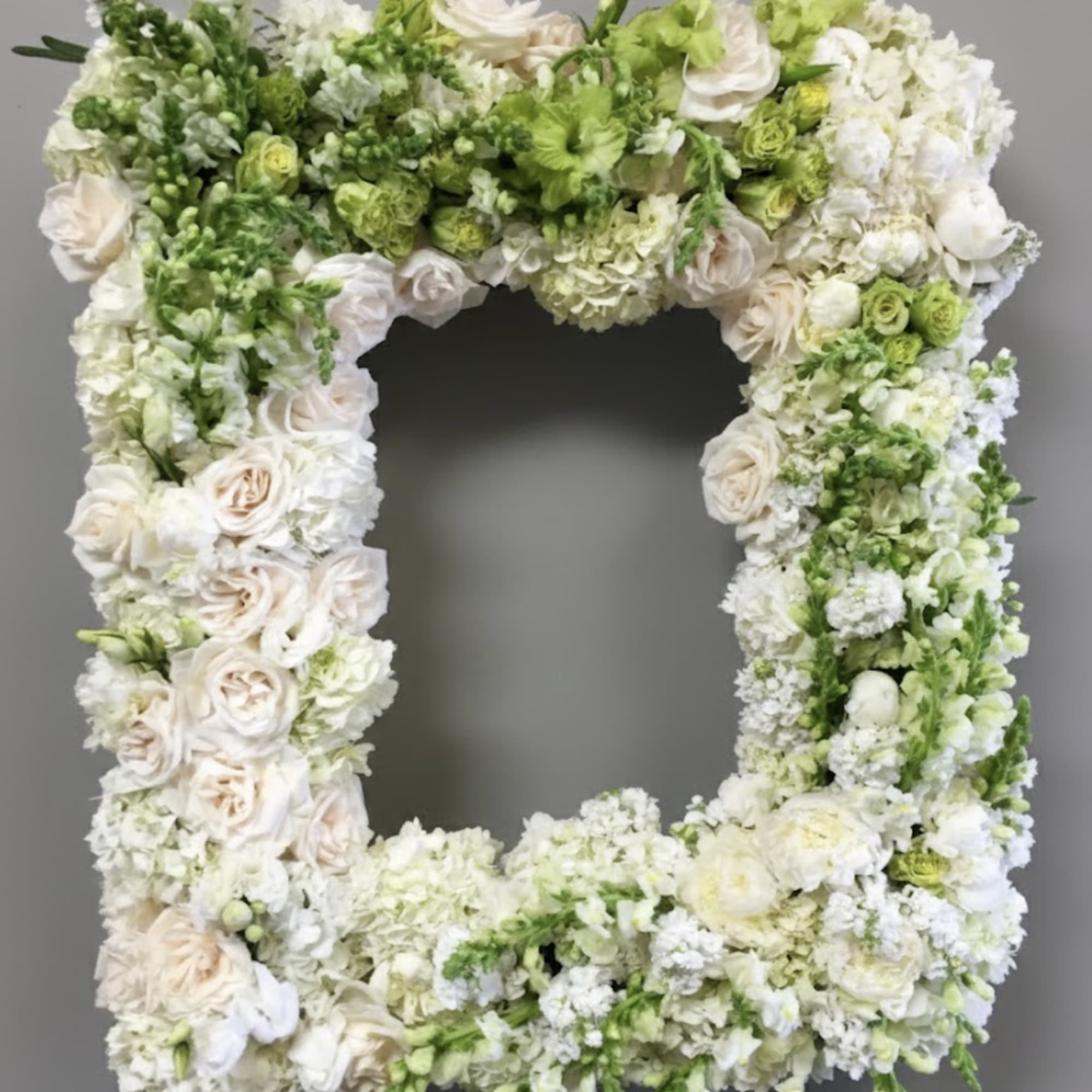 This frame includes white and green roses as well as matching snapdragons.