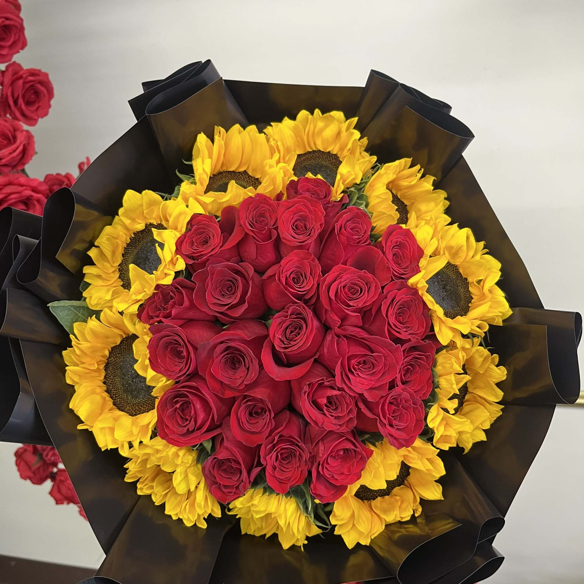 This bouquet features lush red roses at its center, surrounded by a