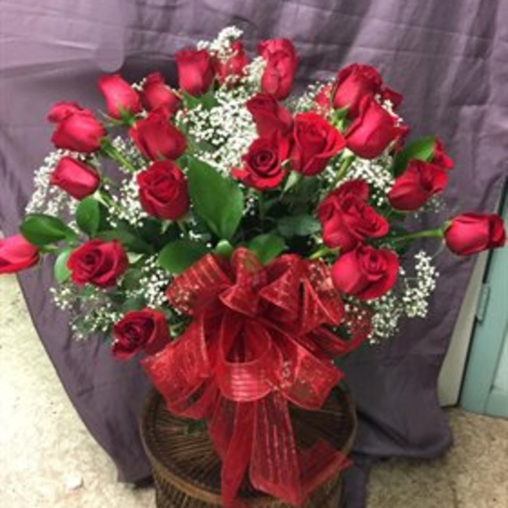 An impressive presentation of two dozen fragrant, long-stemmed red roses accented with