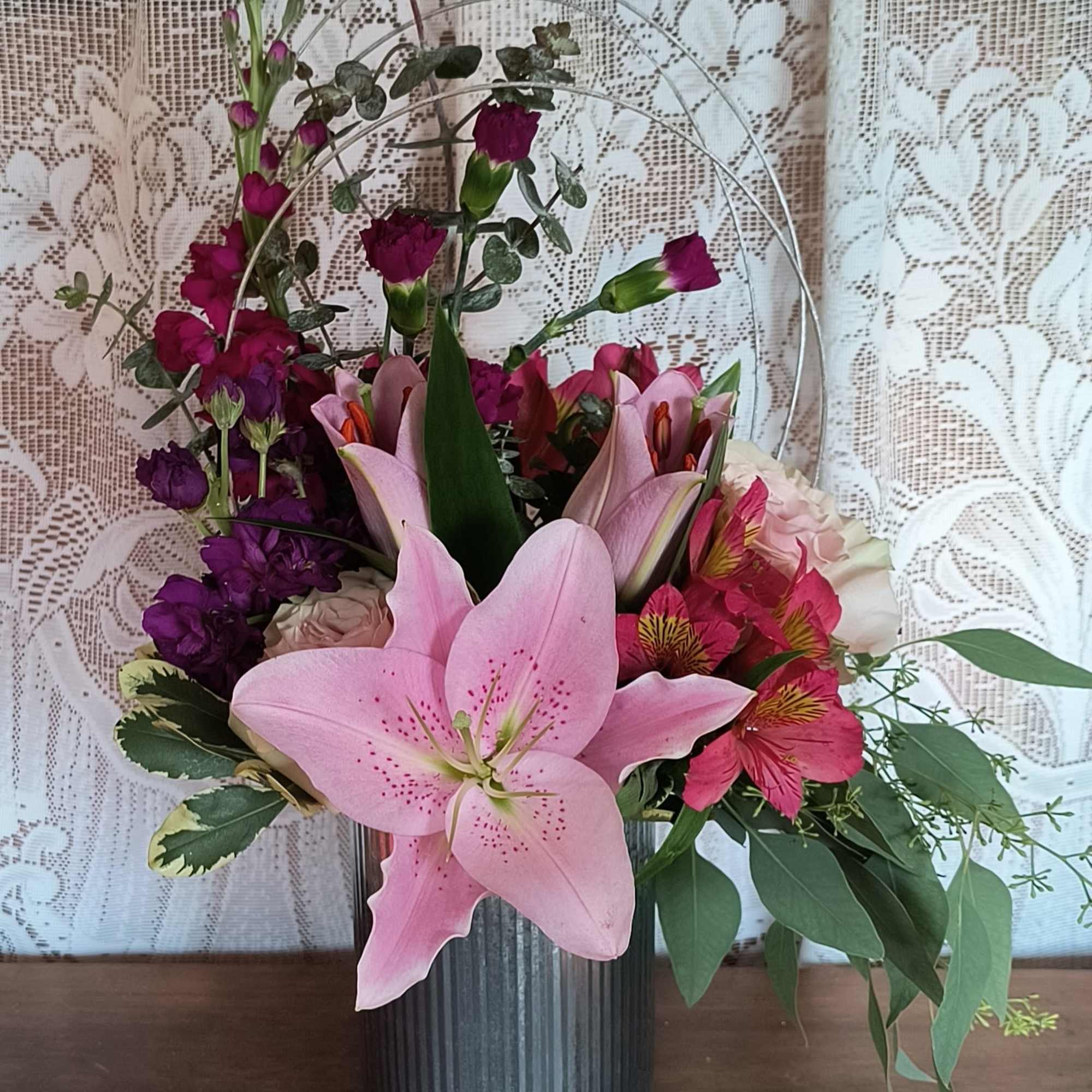 A trendy design of garden flowers to include stock, lily, roses and