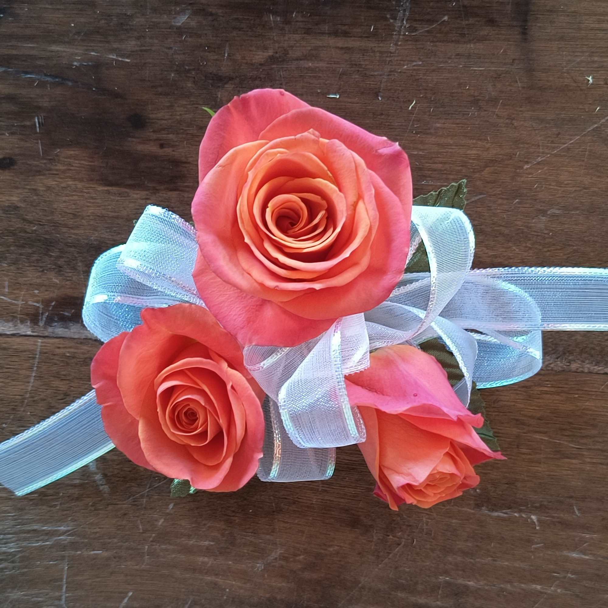 A designers choice wrist corsage of orange spray roses, add as many