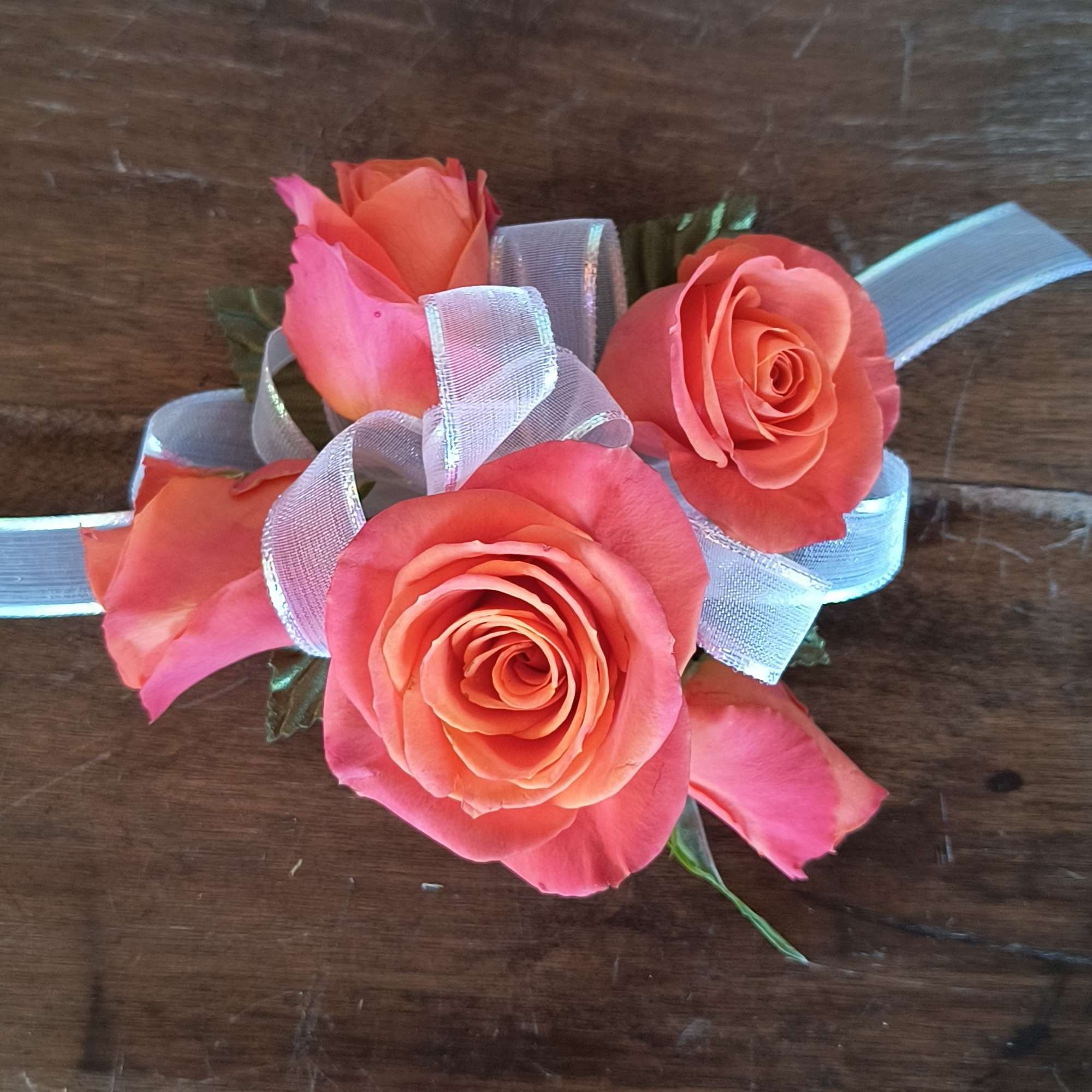 A designers choice wrist corsage of orange spray roses, add as many
