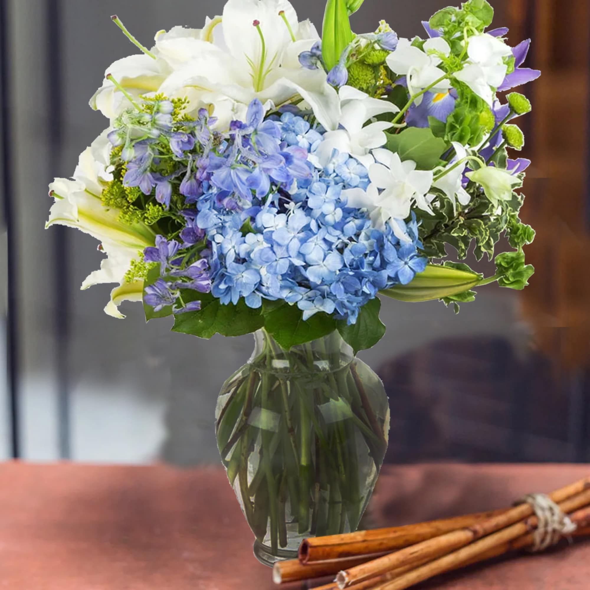 This arrangement contains delphinium, bells of ireland, asiatic lilies, hydrangea, blue iris