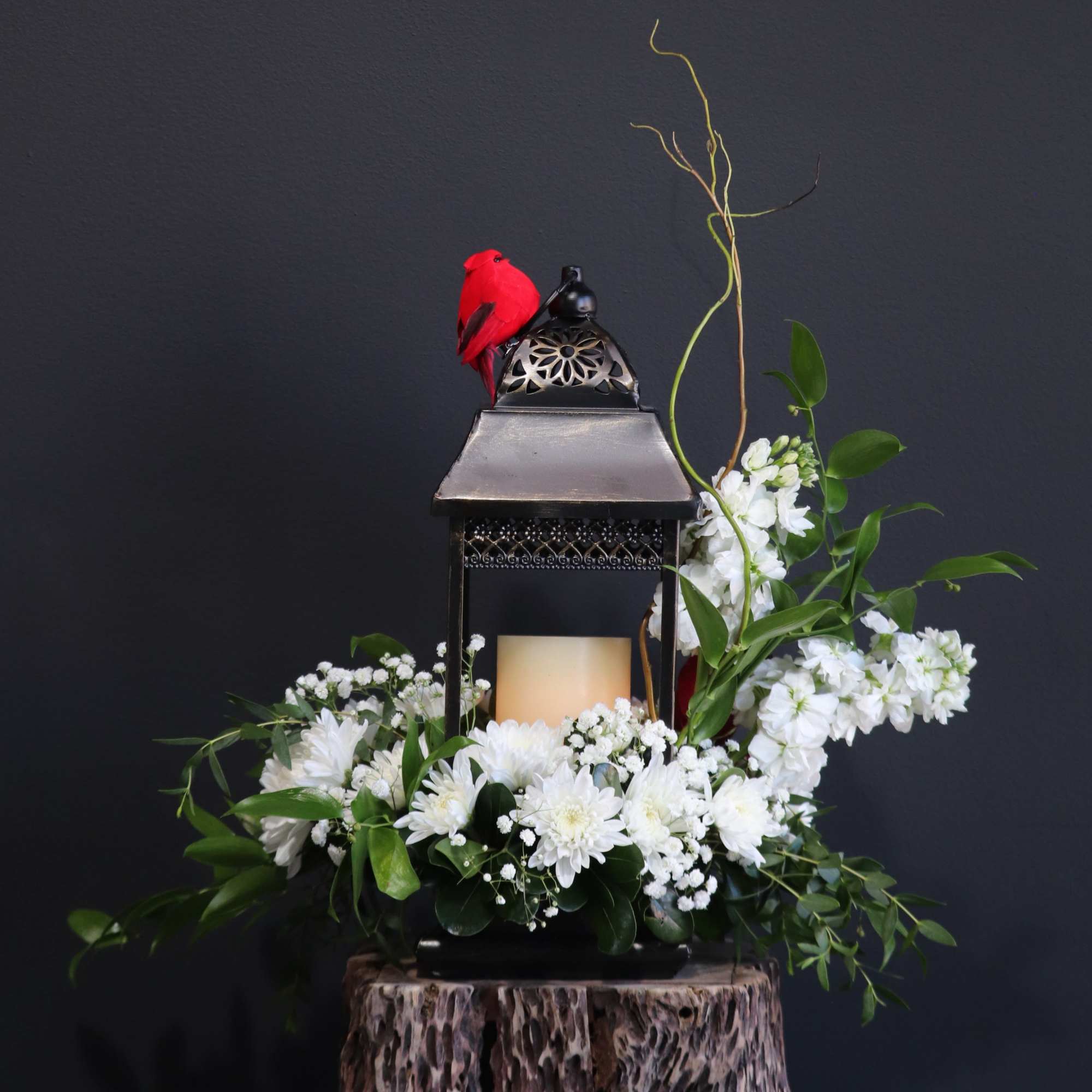 This beautiful sympathy flower arrangement is adorned with a cardinal on a