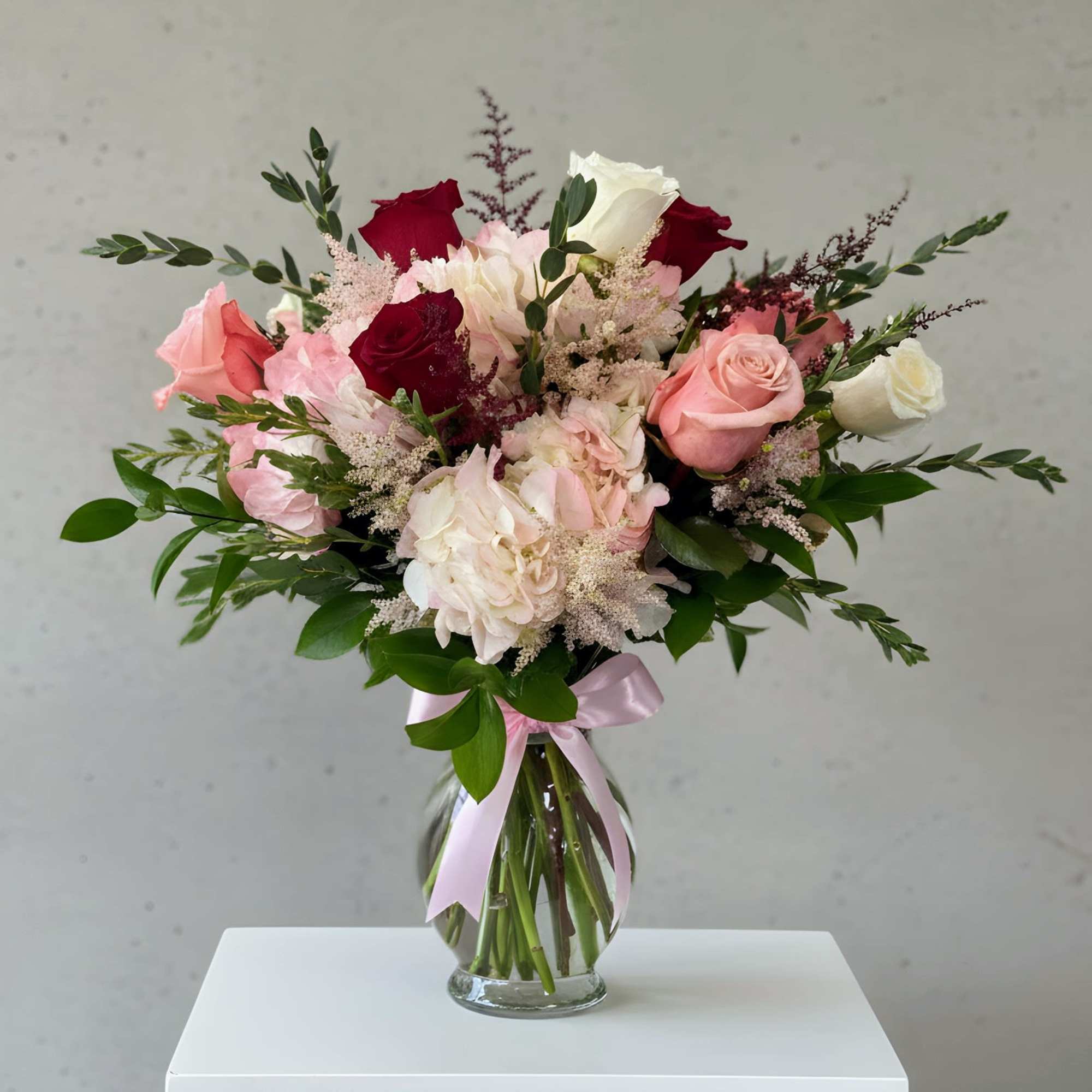 A beautifully designed arrangement featuring red, soft white and blush roses paired