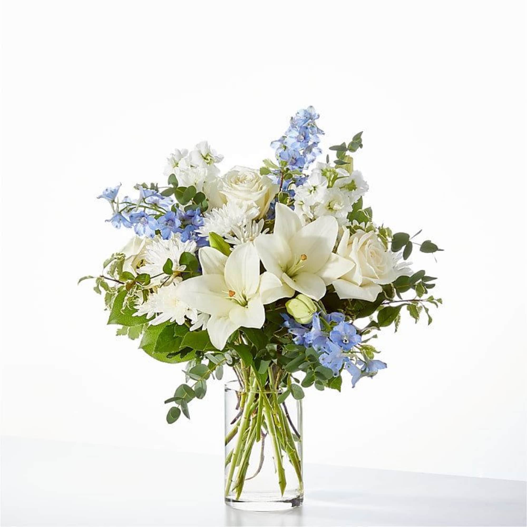 White roses, delicate delphinium, and blooming lilies come together for a luxurious