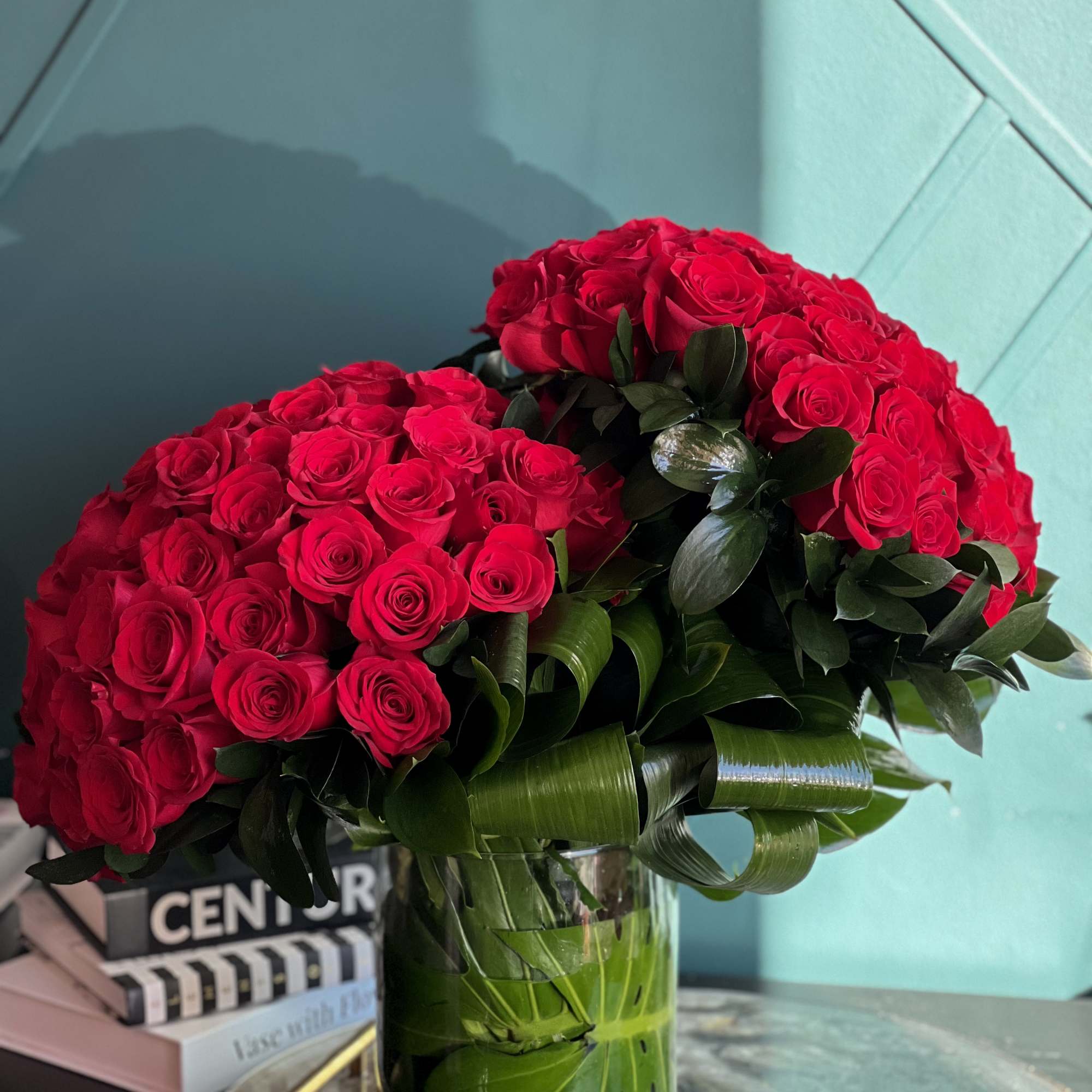 100 premium red roses in a clear vase with greenery accent 