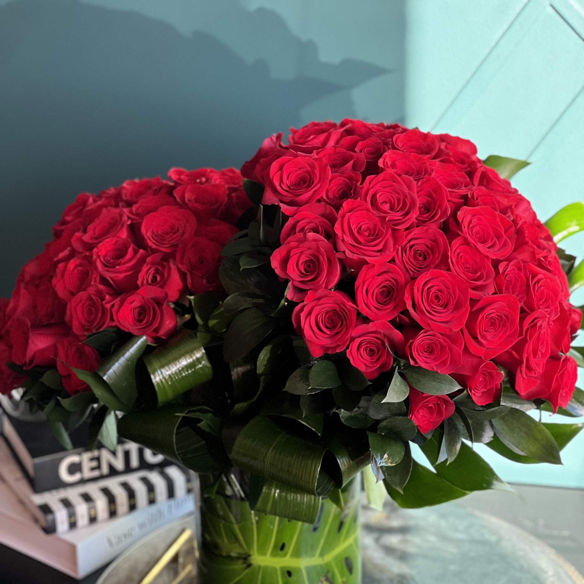 100 premium red roses in a clear vase with greenery accent 